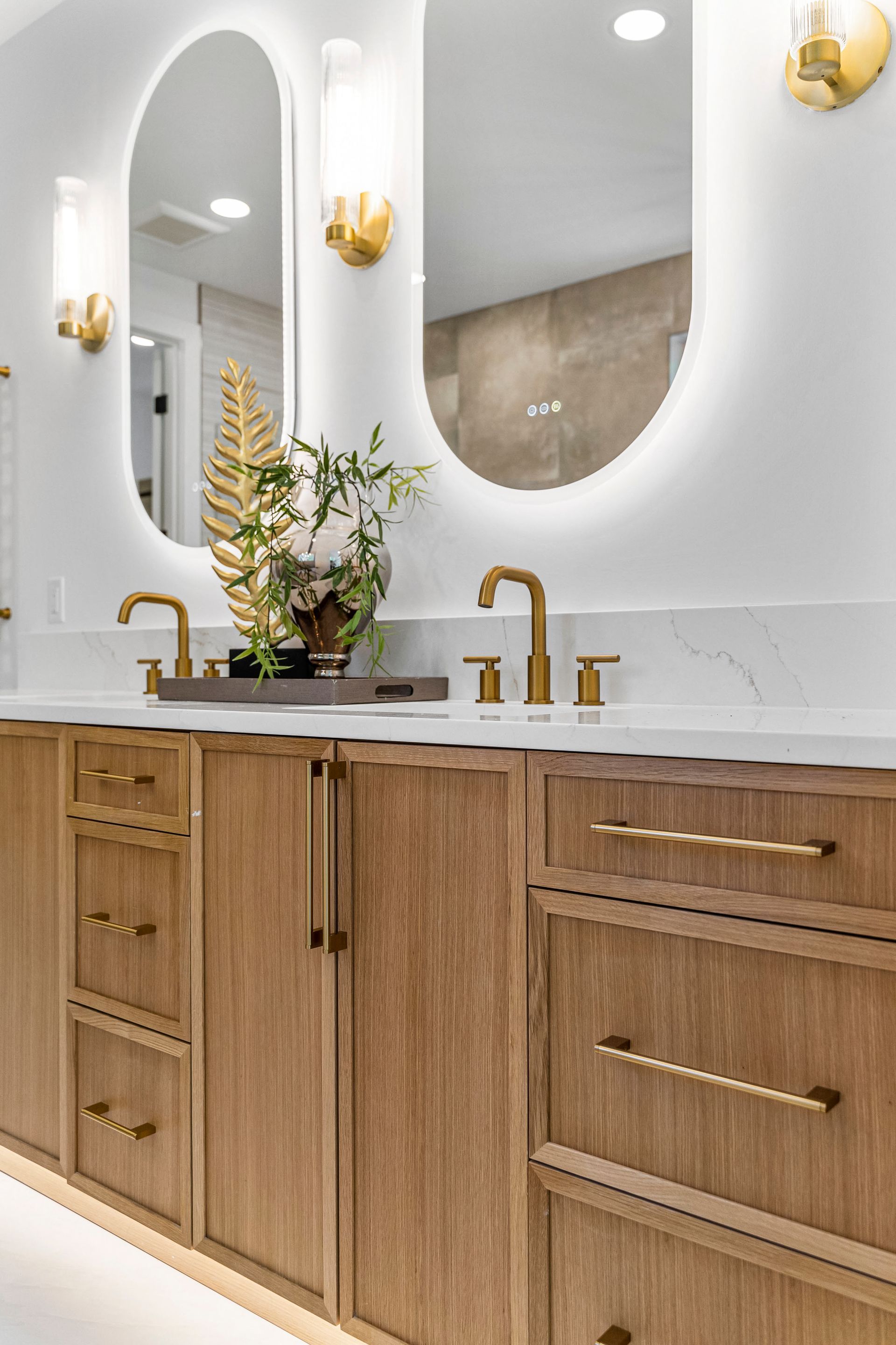 A bathroom with two sinks , two mirrors , and wooden cabinets.