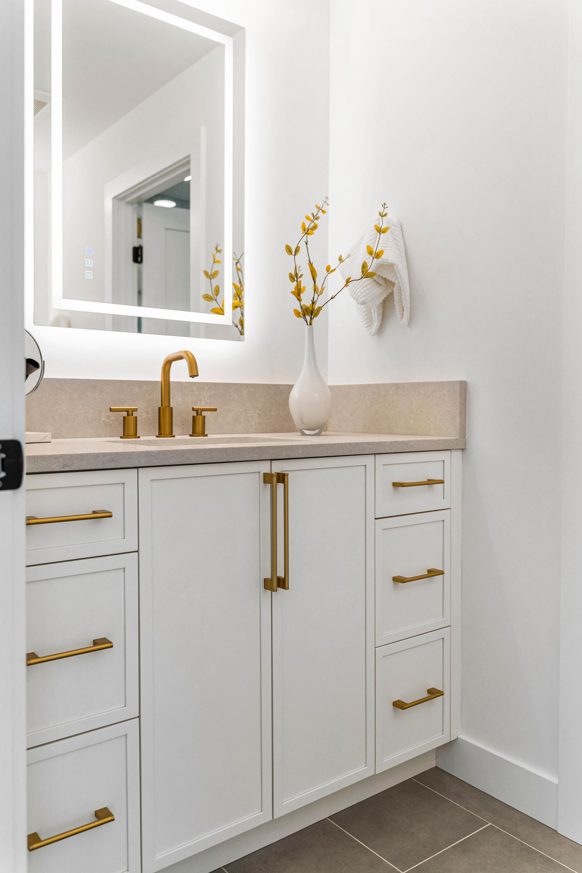 A bathroom with a sink , mirror , cabinets and drawers.