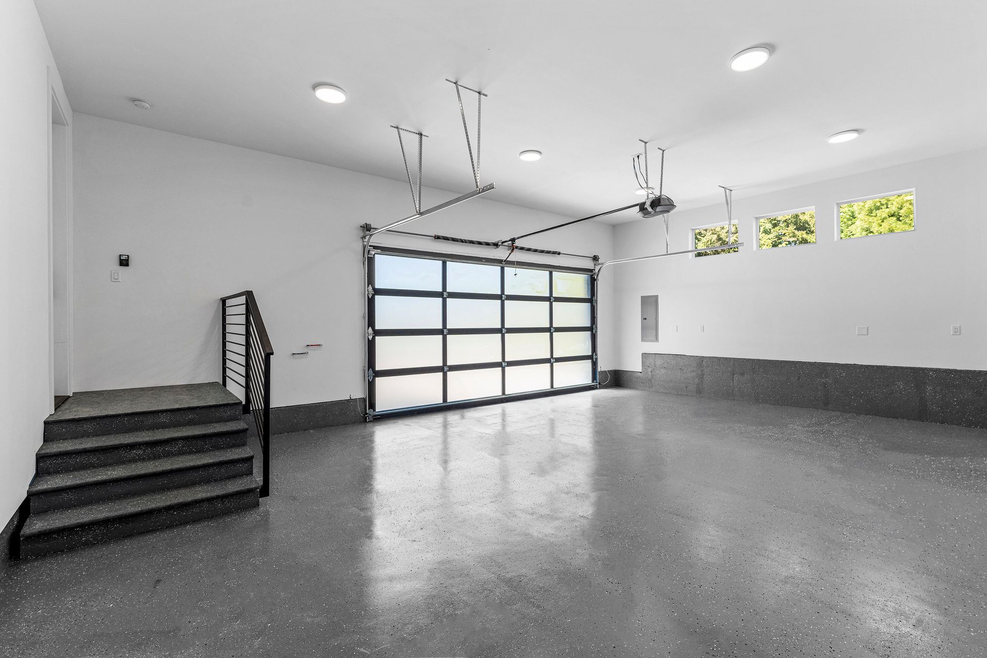 An empty garage with a garage door open and stairs leading up to it.