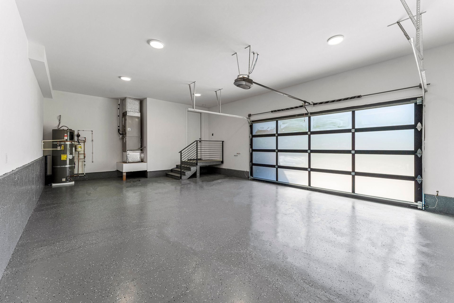 An empty garage with a glass garage door and stairs.