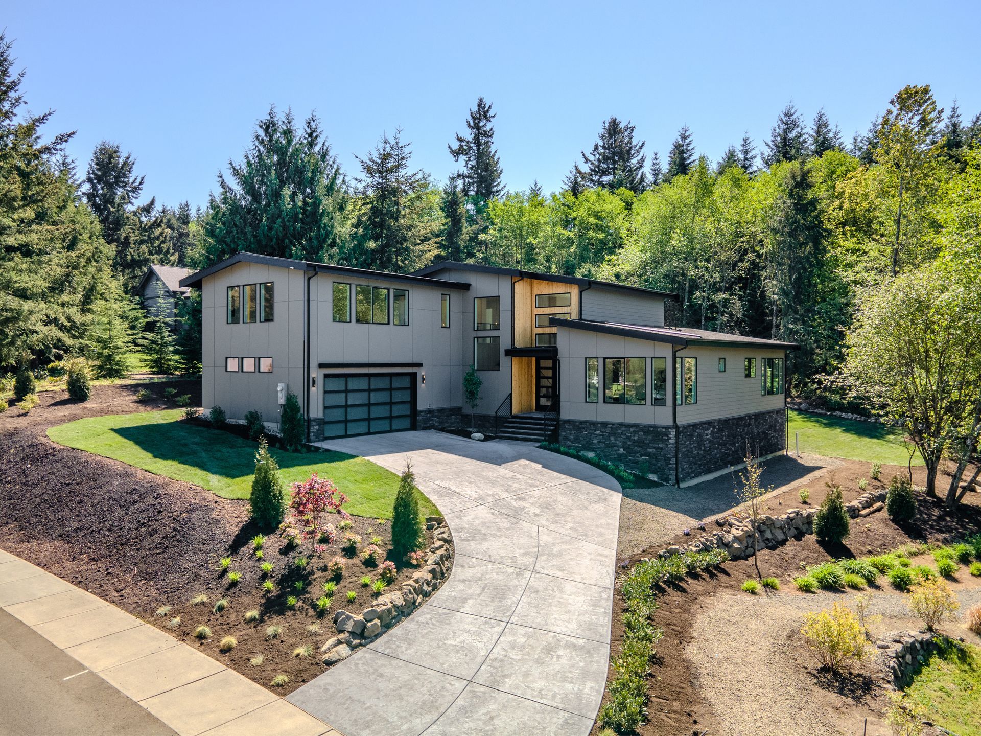 A large house with a driveway leading to it is surrounded by trees.