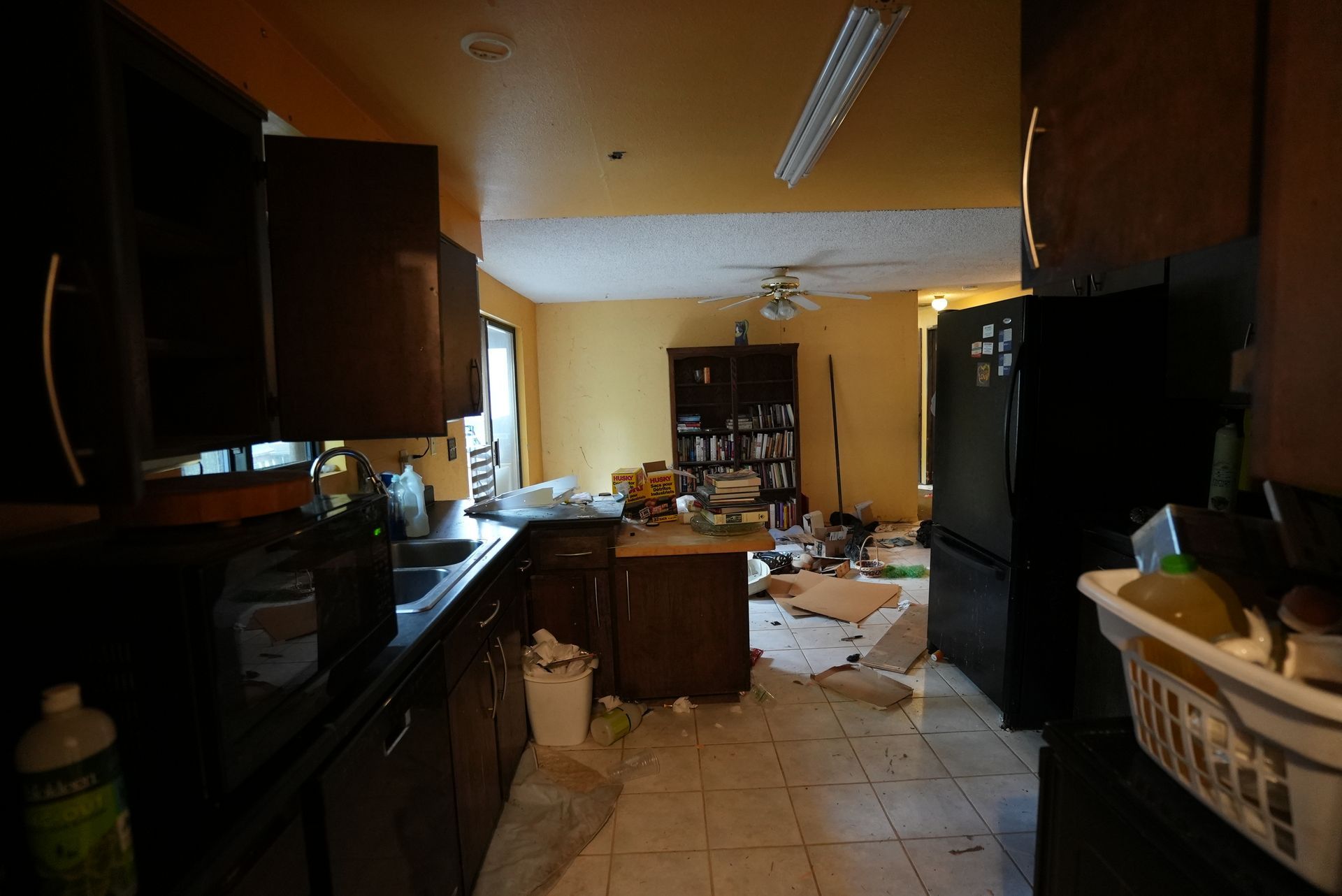 A kitchen with a black refrigerator and a white laundry basket