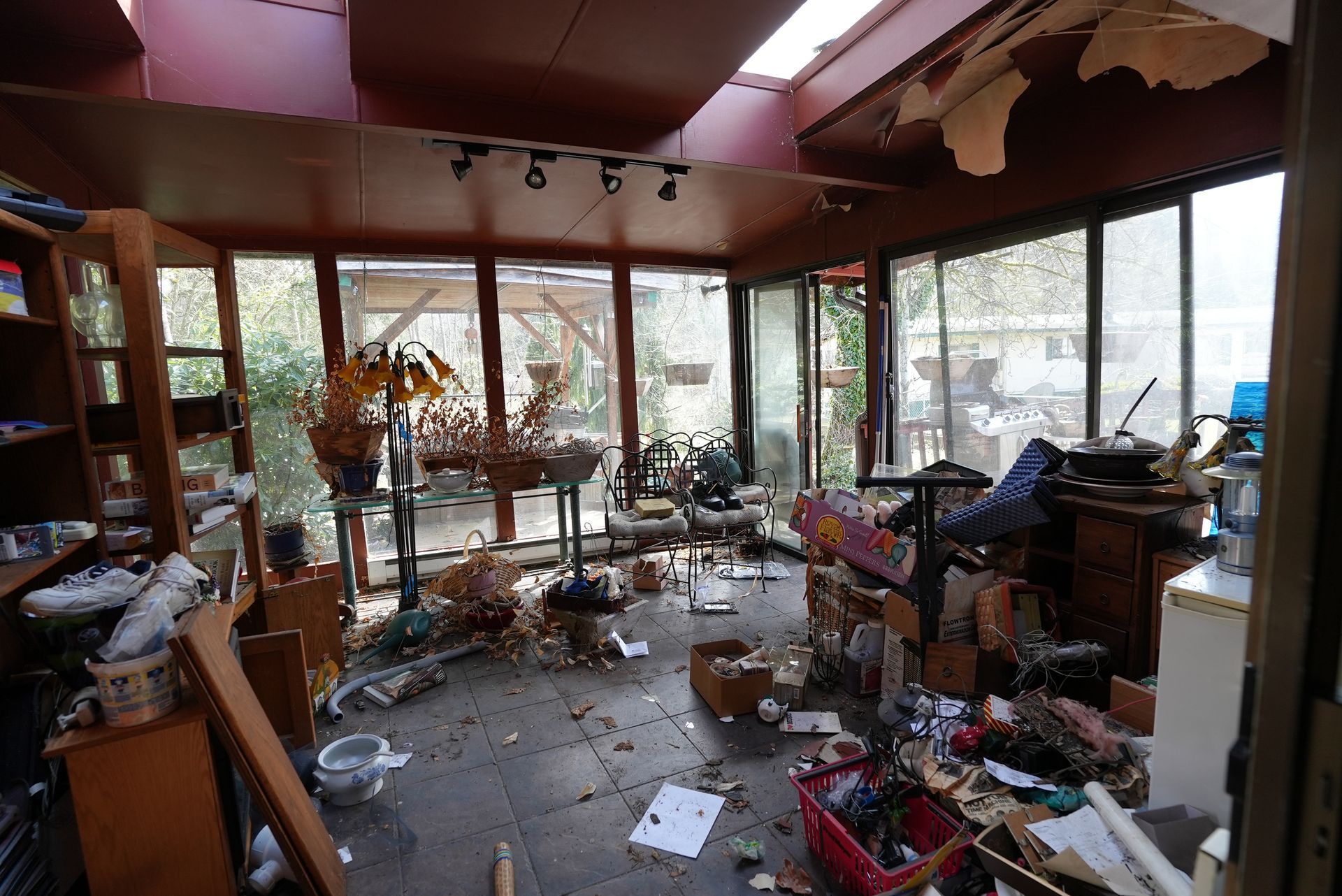 A messy room with a lot of furniture and boxes on the floor.