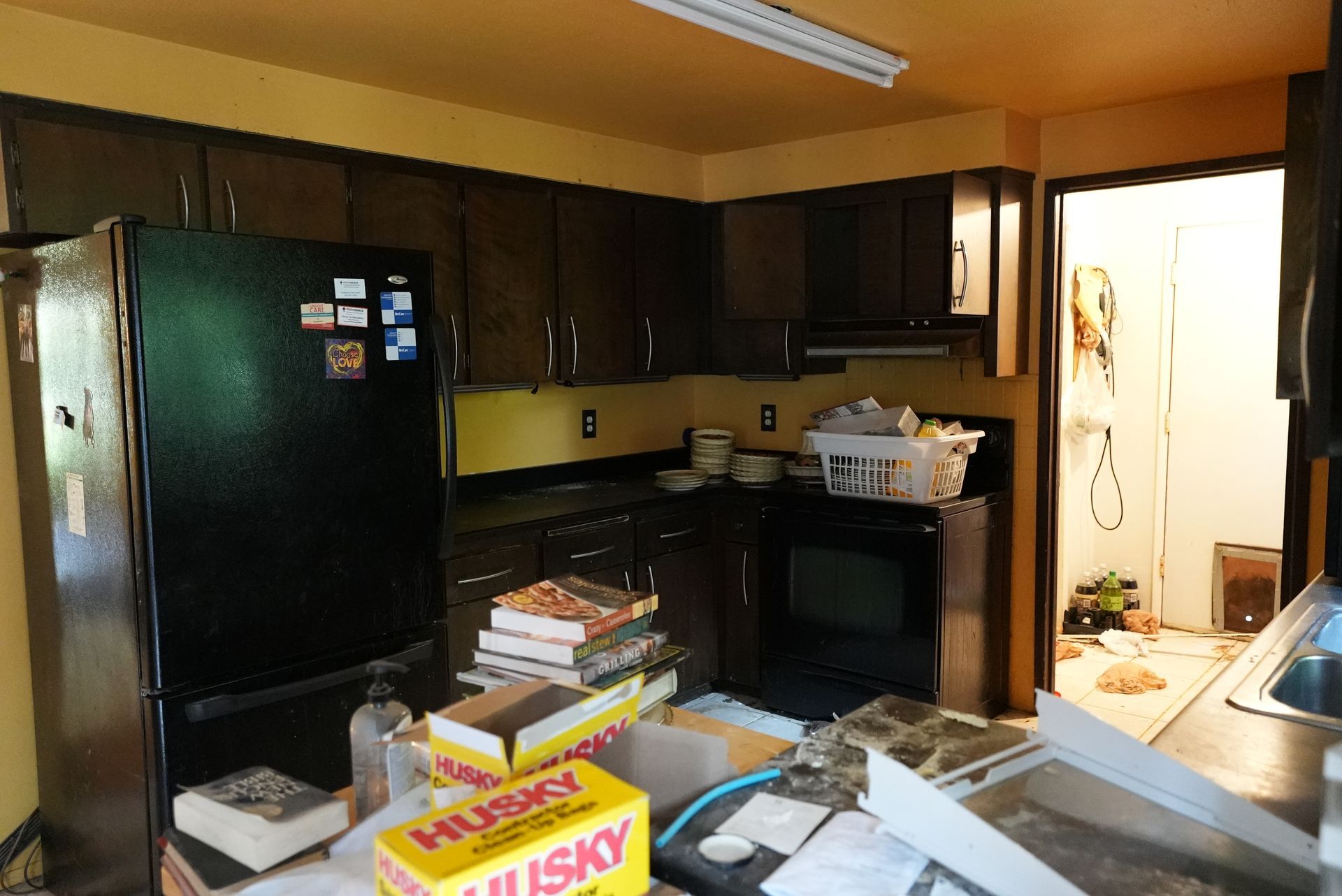 A kitchen with a black refrigerator and a yellow box that says husky