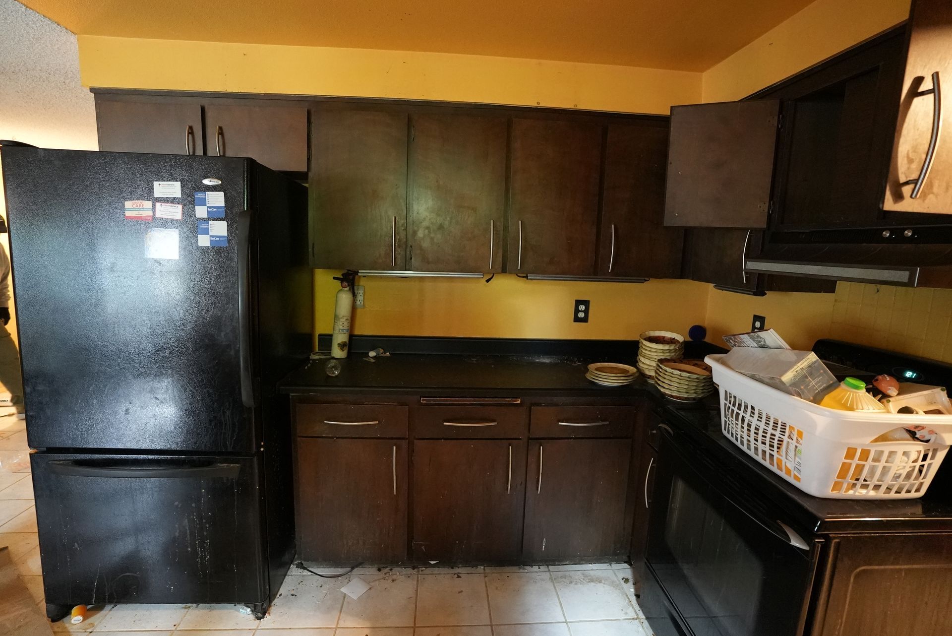 A kitchen with a black refrigerator and a white laundry basket
