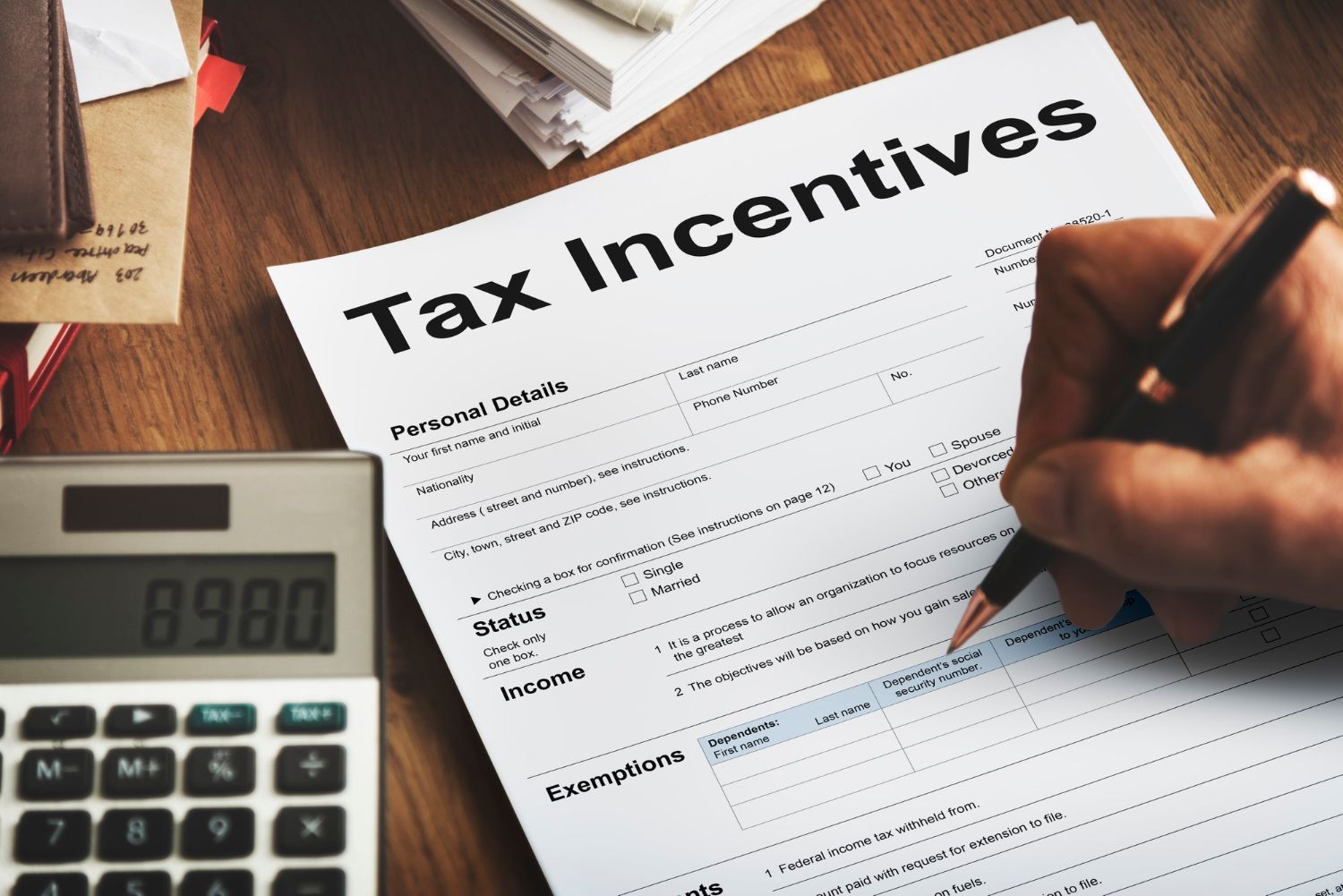 A person is filling out a tax incentive form next to a calculator