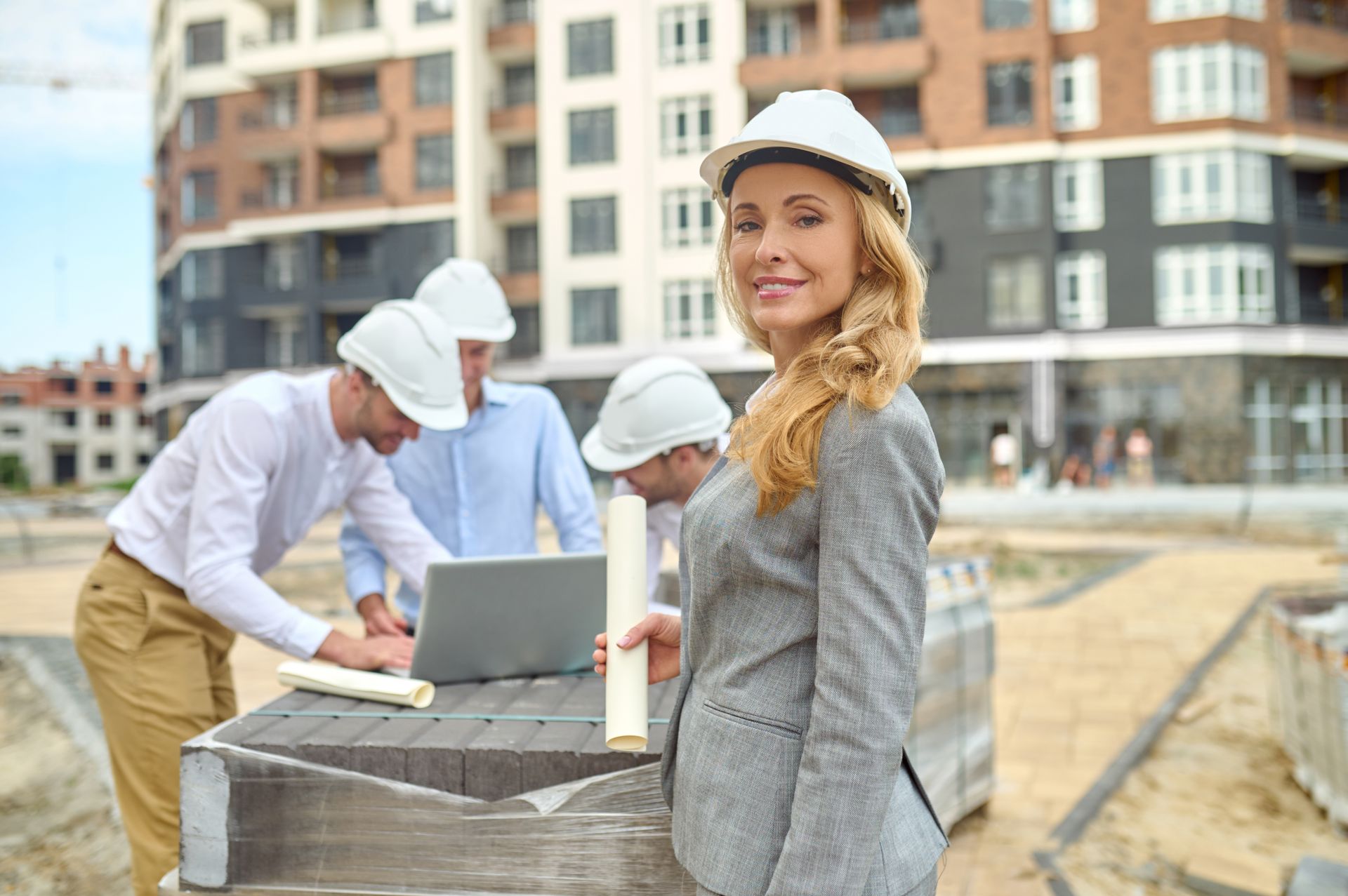 A woman is standing in front of a group of construction workers on a construction site.