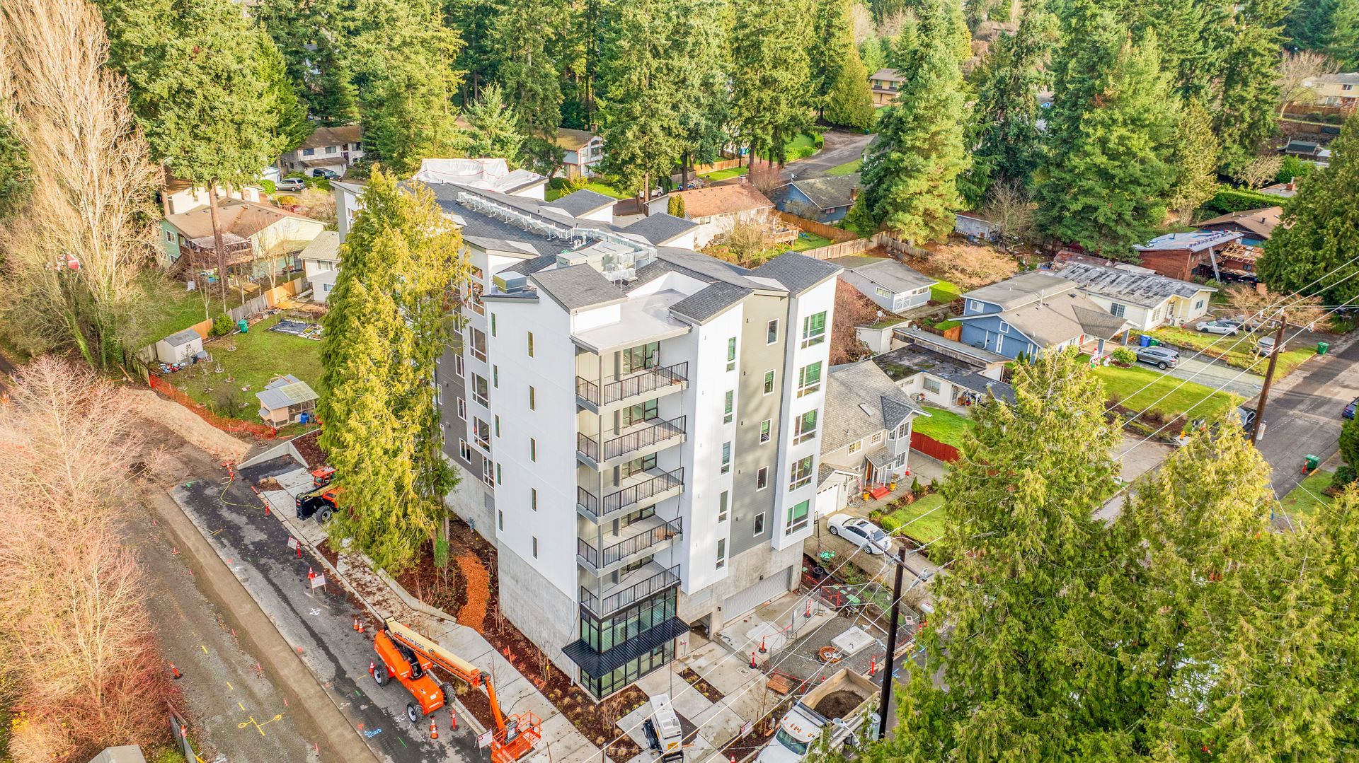 An aerial view of a building under construction in a residential area surrounded by trees.
