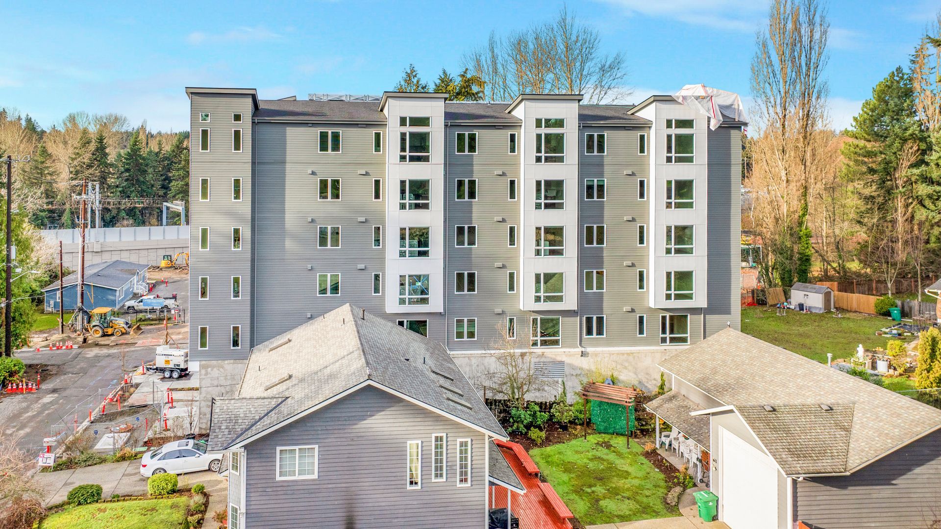An aerial view of a large apartment building with a house in front of it.
