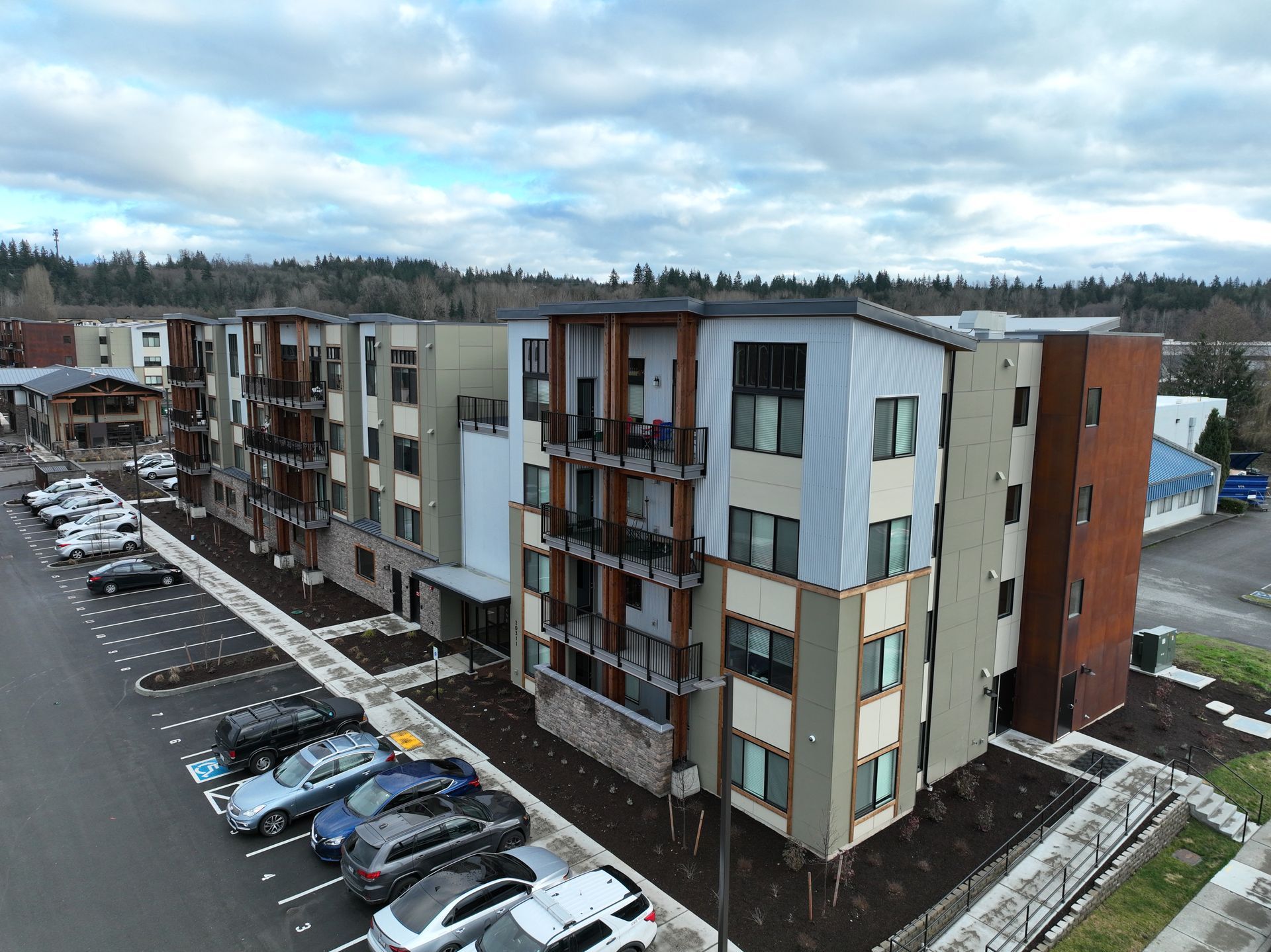 An aerial view of a large apartment building with cars parked in front of it.