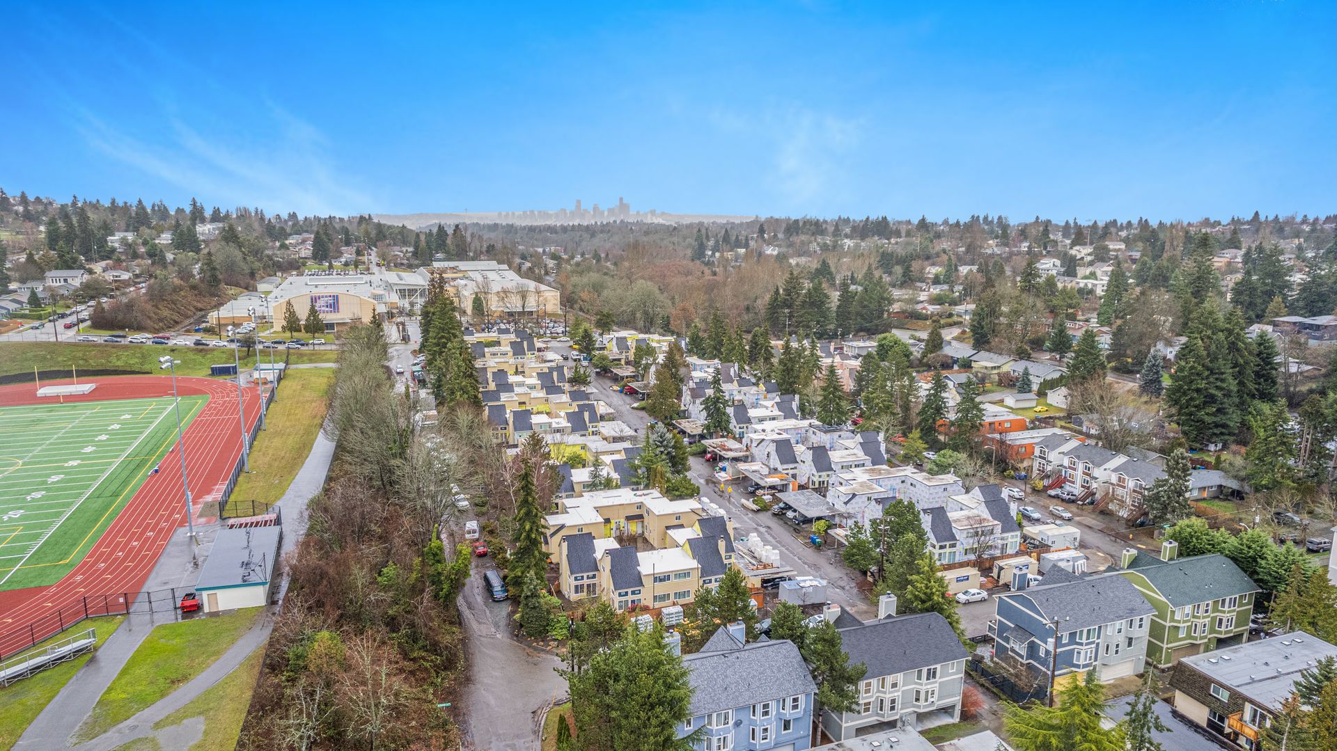 An aerial view of a residential area with a football field in the background.