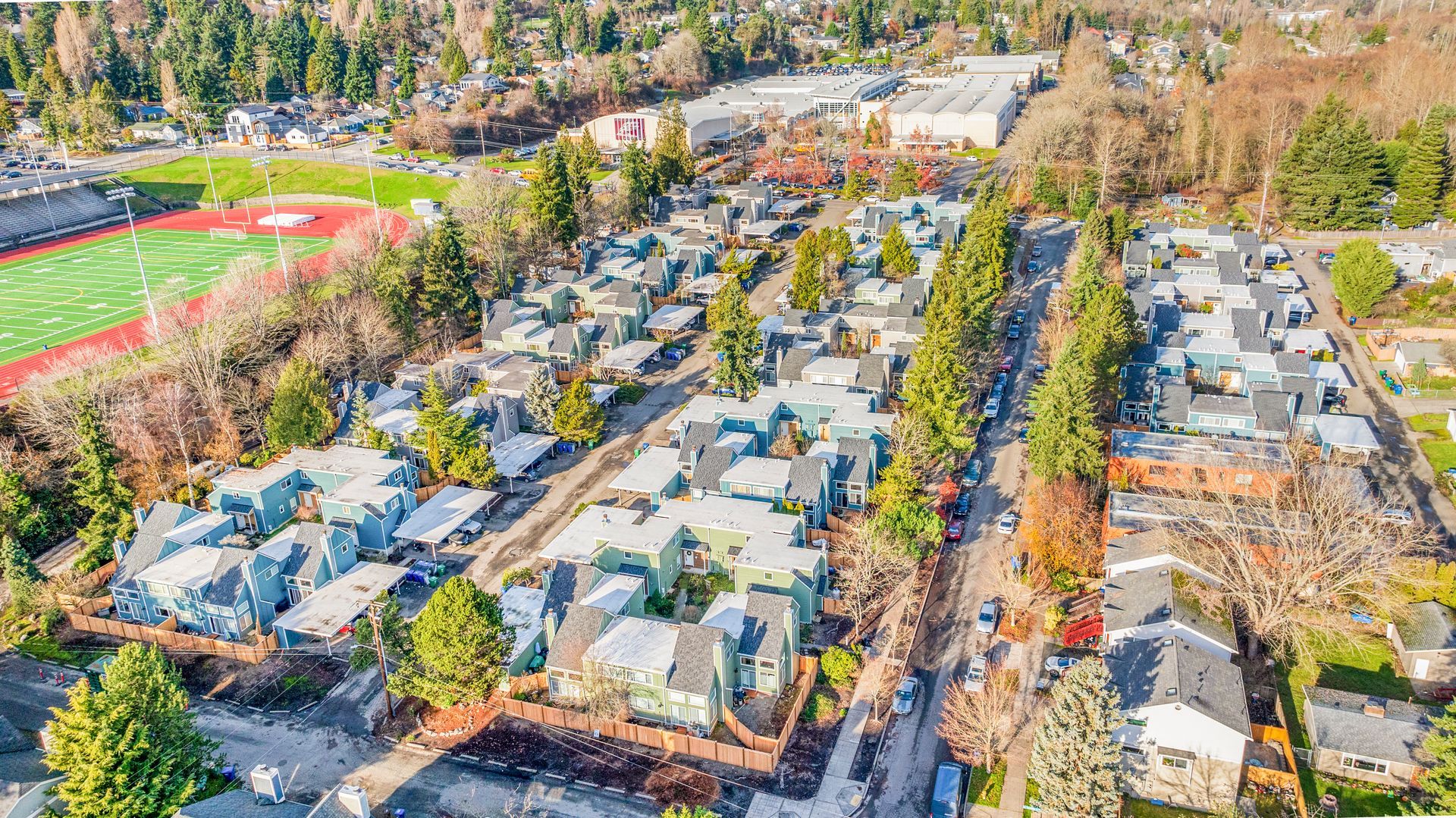 An aerial view of a residential area with a baseball field in the background.