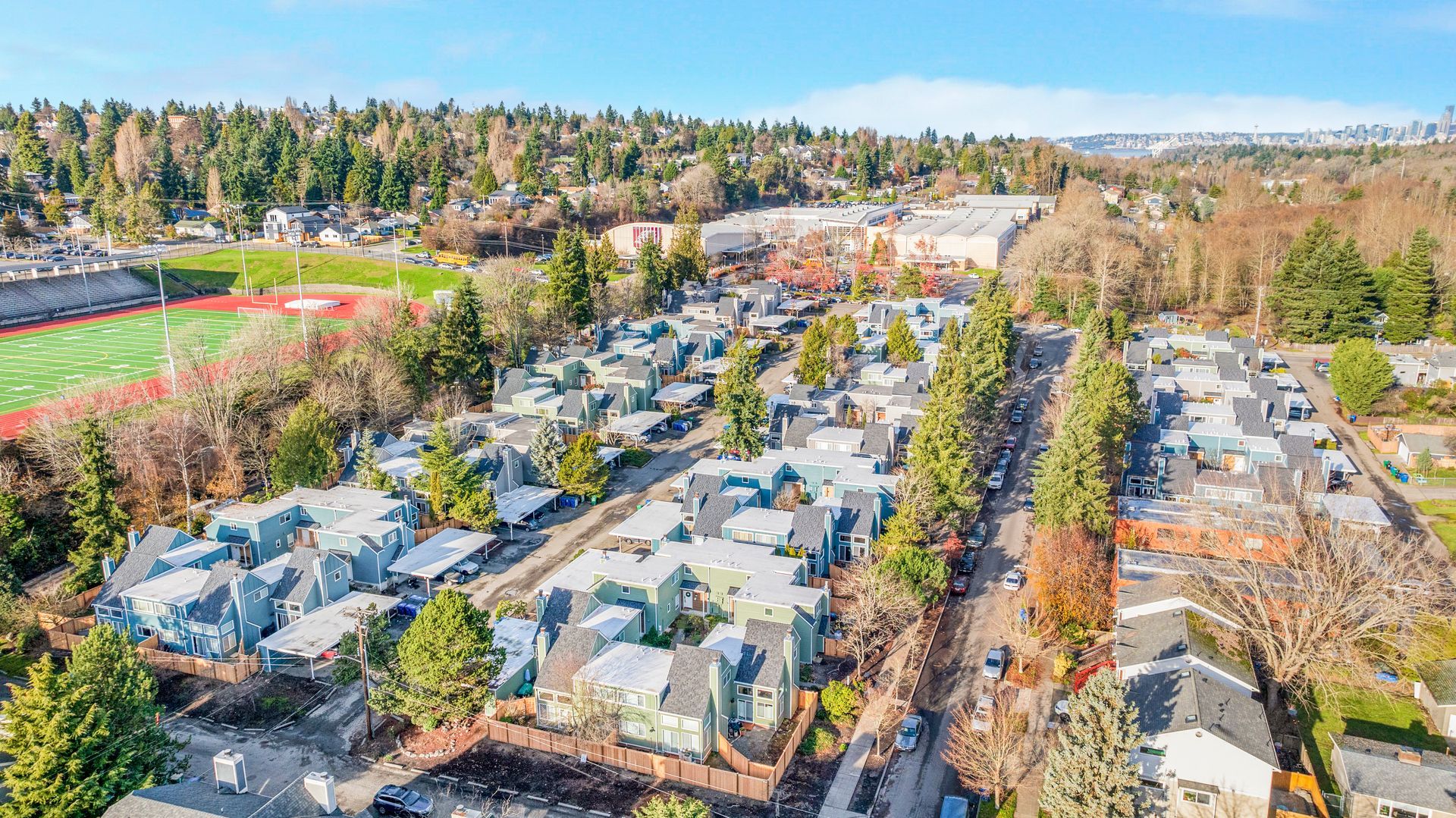 An aerial view of a residential neighborhood with a football field in the background.