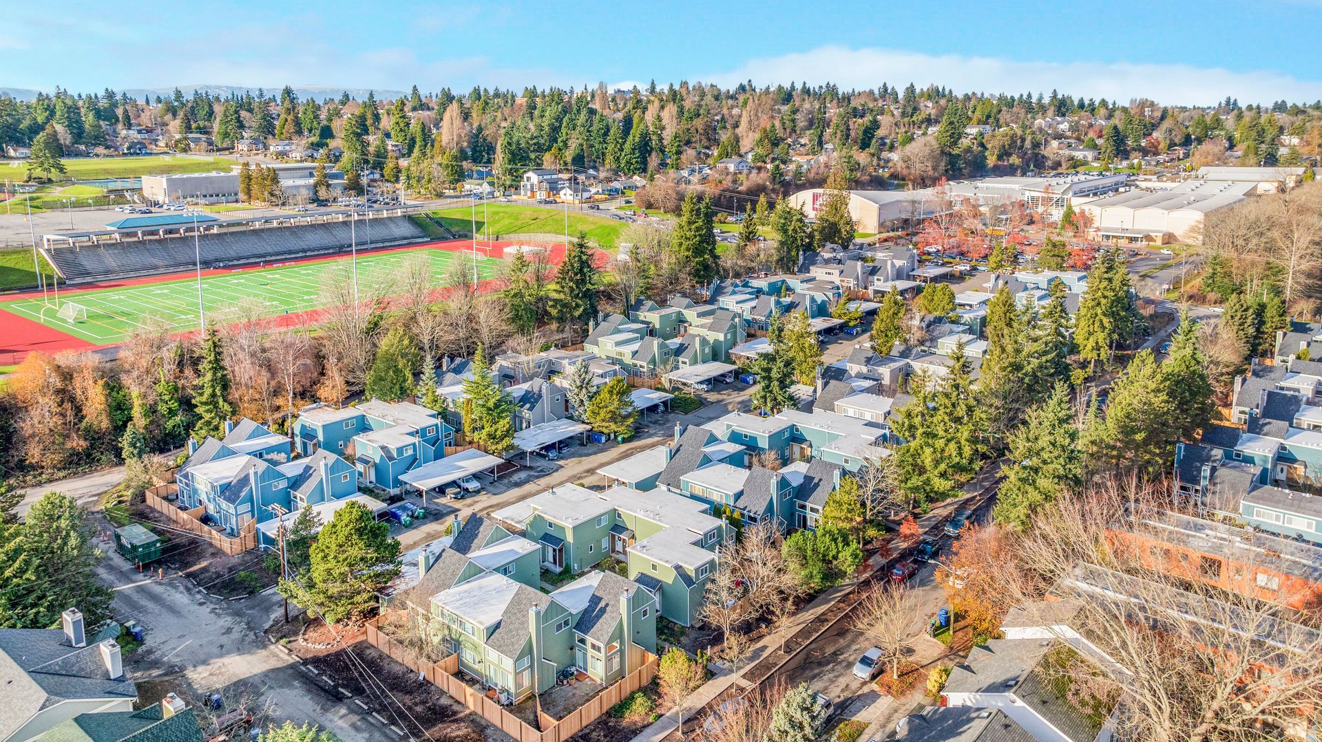 An aerial view of a residential area with a football field in the background.