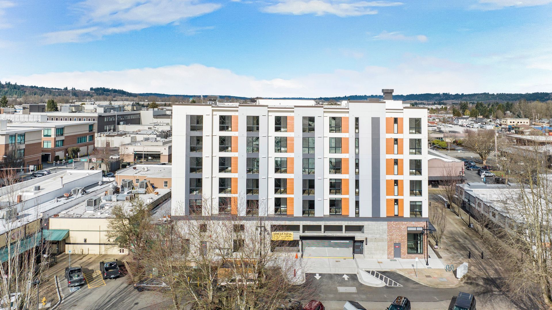An aerial view of a large building in a city with cars parked in front of it.