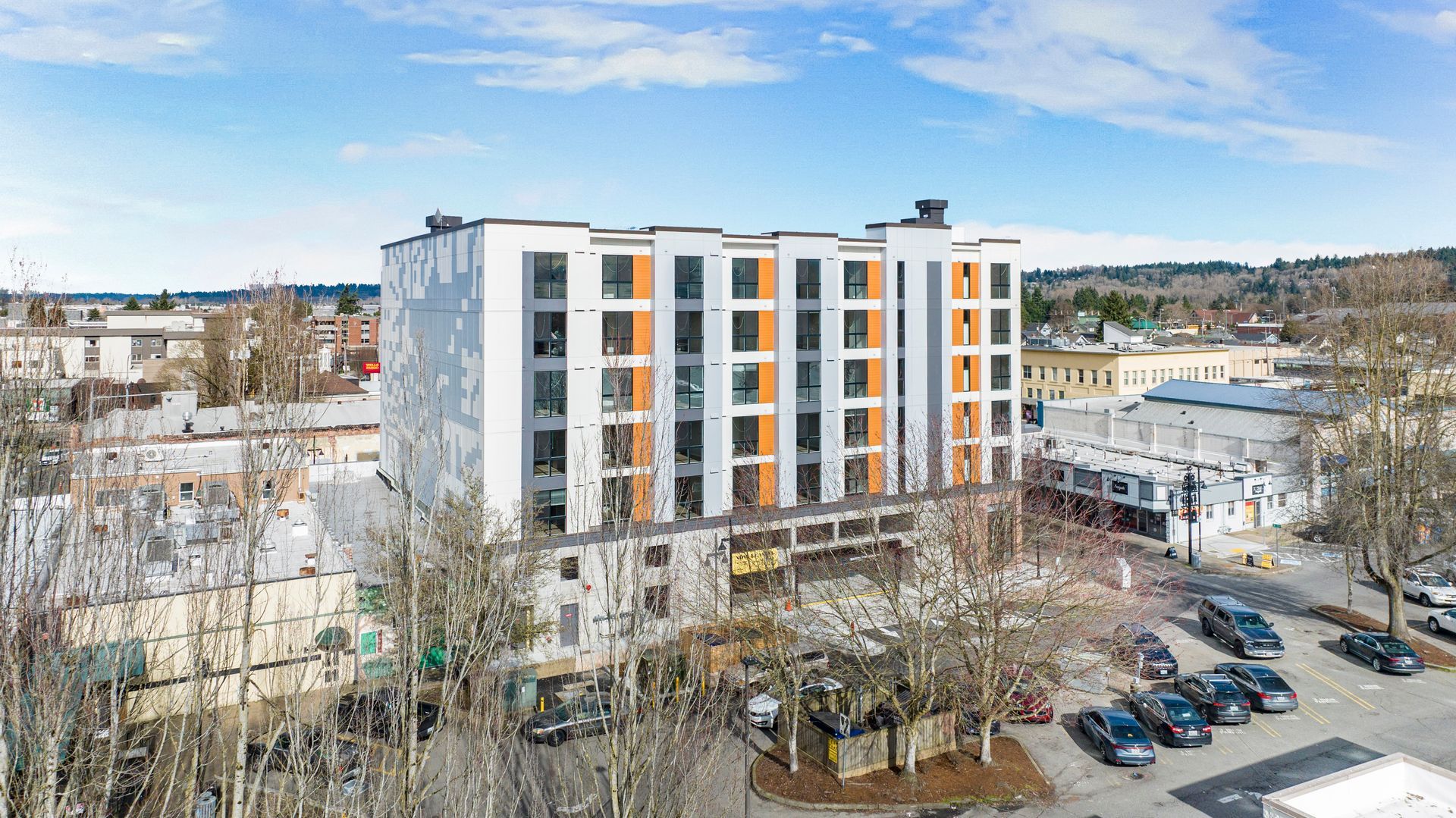 An aerial view of a large building in a city with cars parked in front of it.