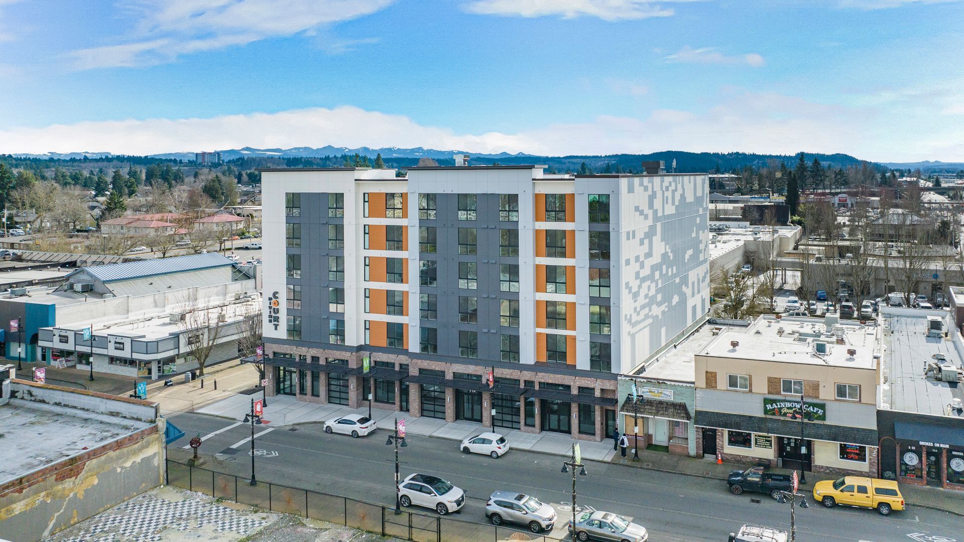 An aerial view of a large building in a city with cars parked in front of it.