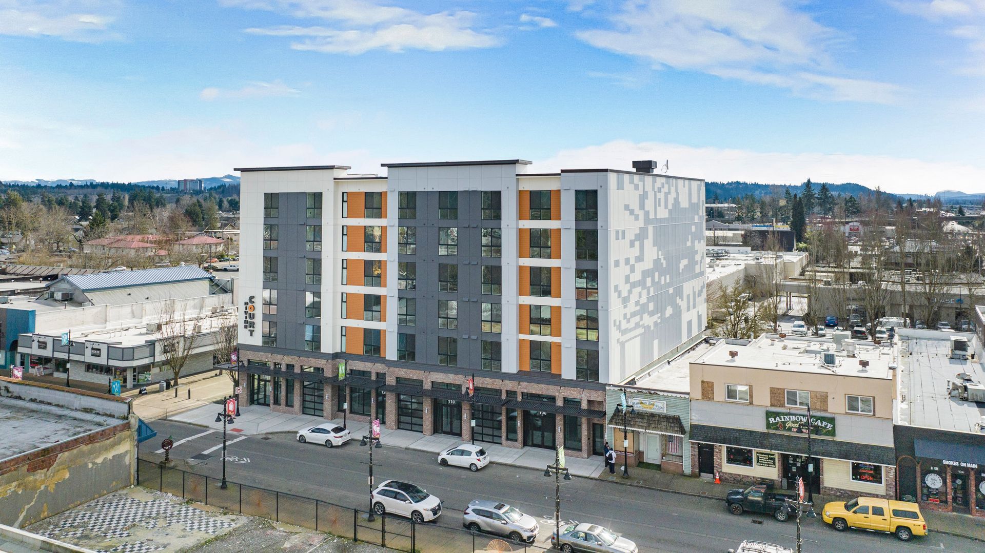 An aerial view of a large building in a city with cars parked in front of it.
