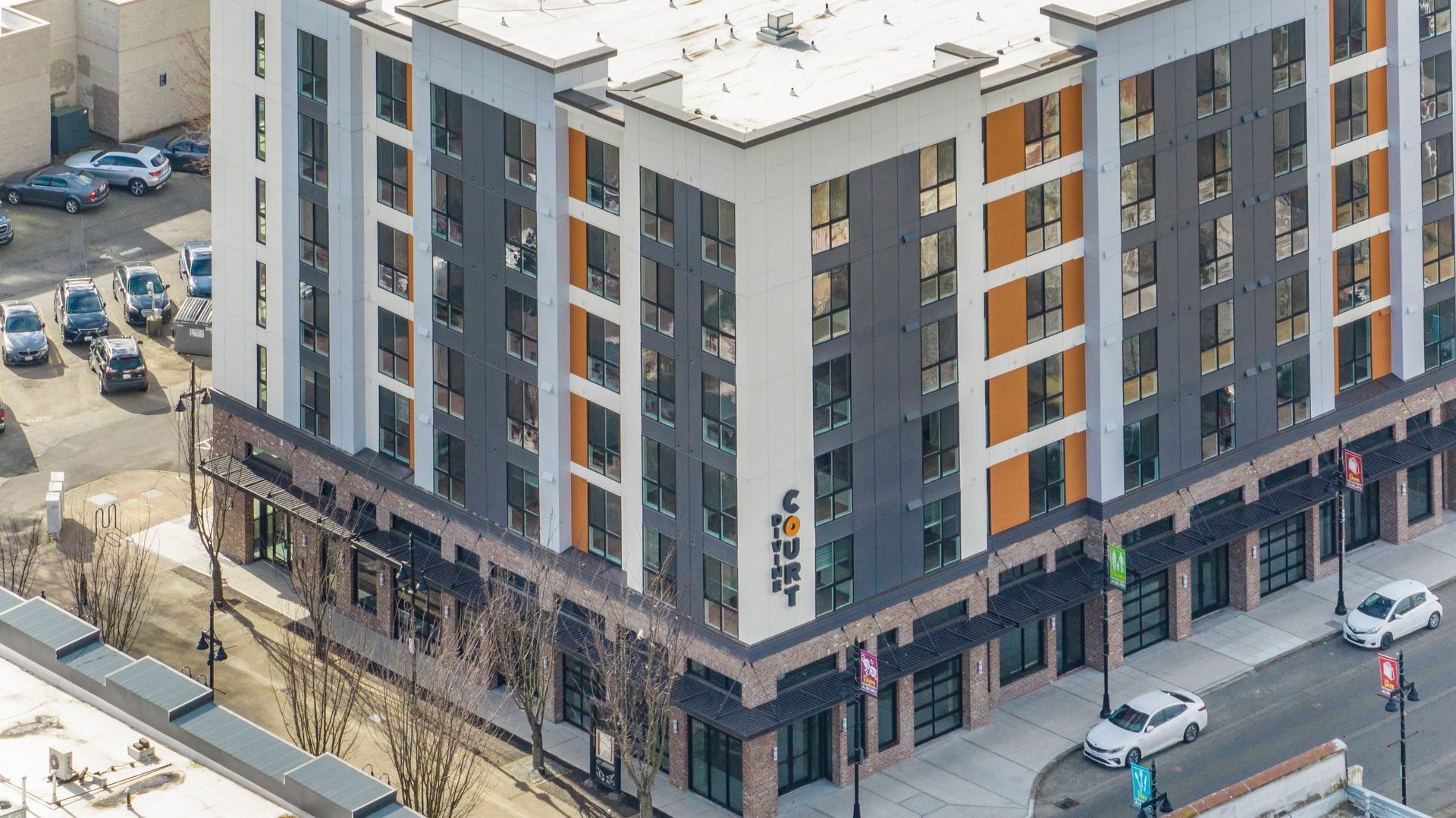 An aerial view of a large apartment building with cars parked in front of it.