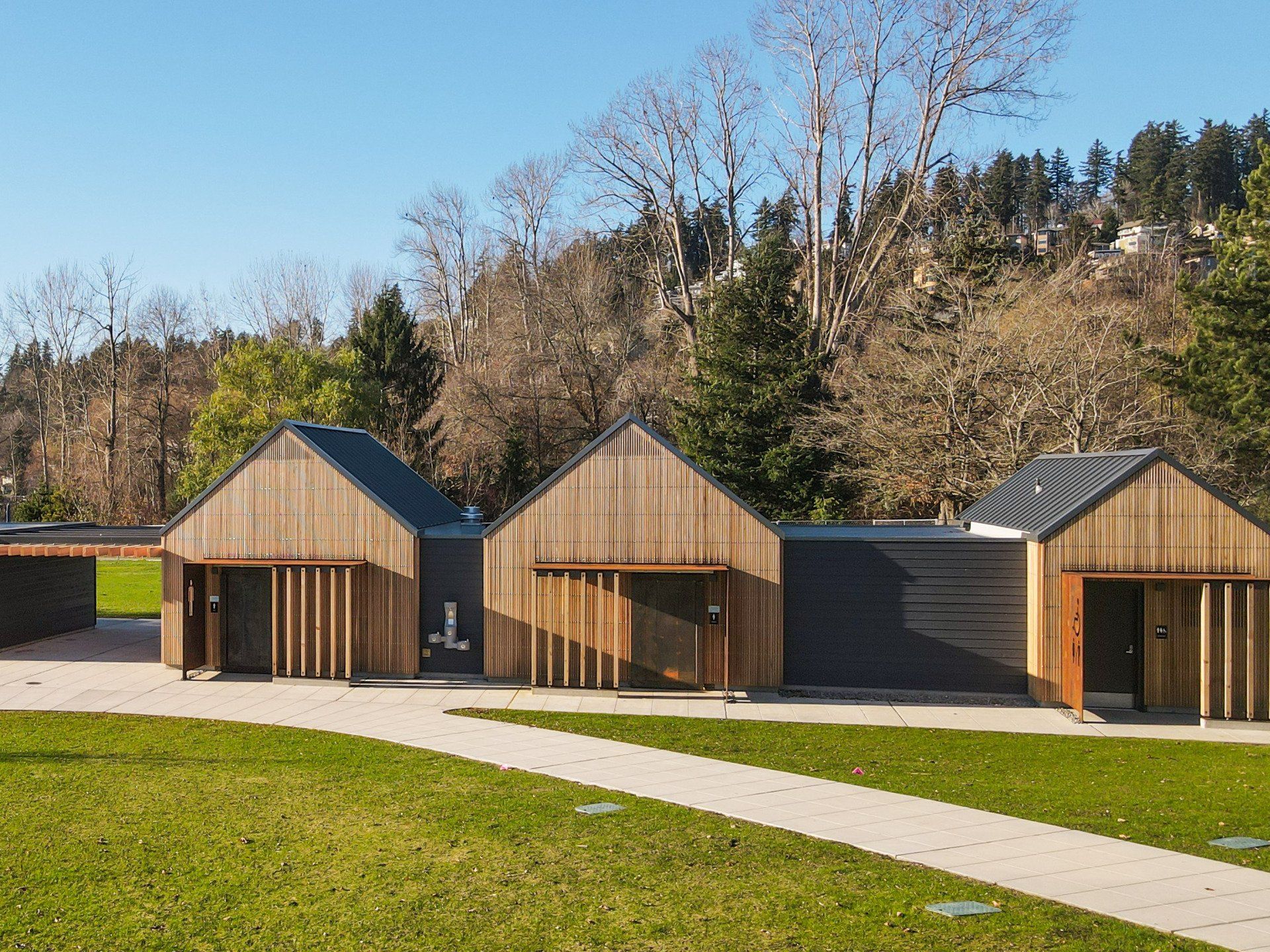 A row of wooden houses are sitting next to each other on a lush green field.