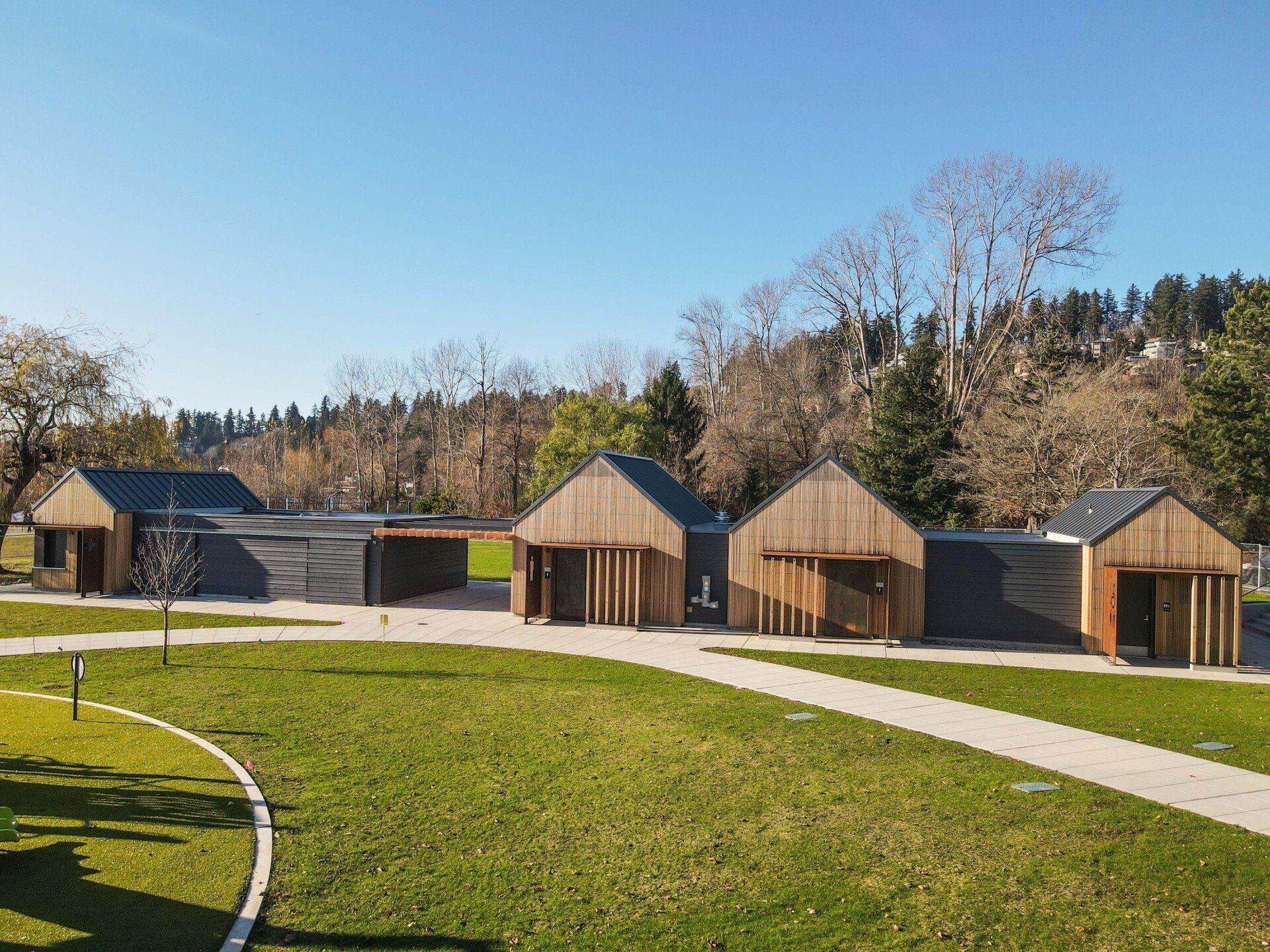 A row of wooden houses are sitting next to each other on a lush green field.