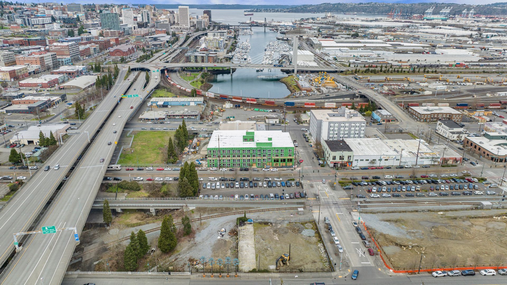 An aerial view of a city with a green building in the middle.