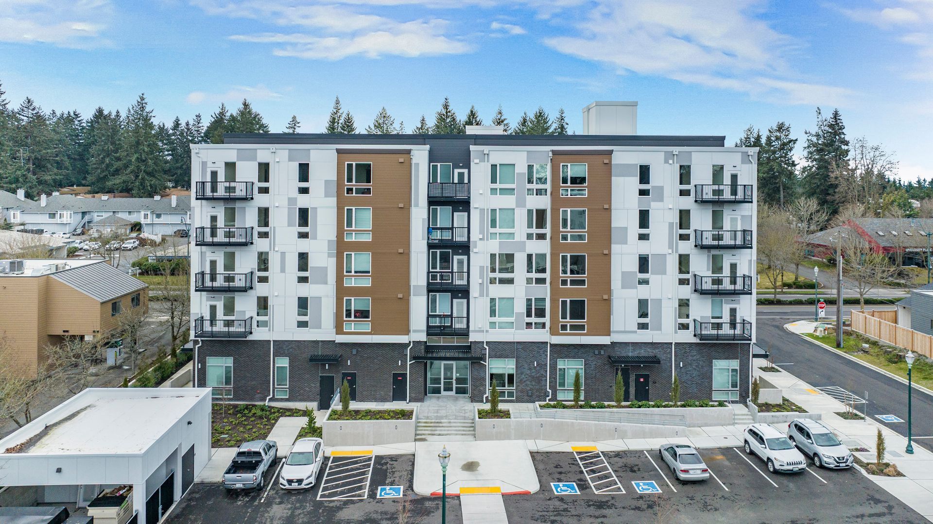 An aerial view of a large apartment building with cars parked in front of it.
