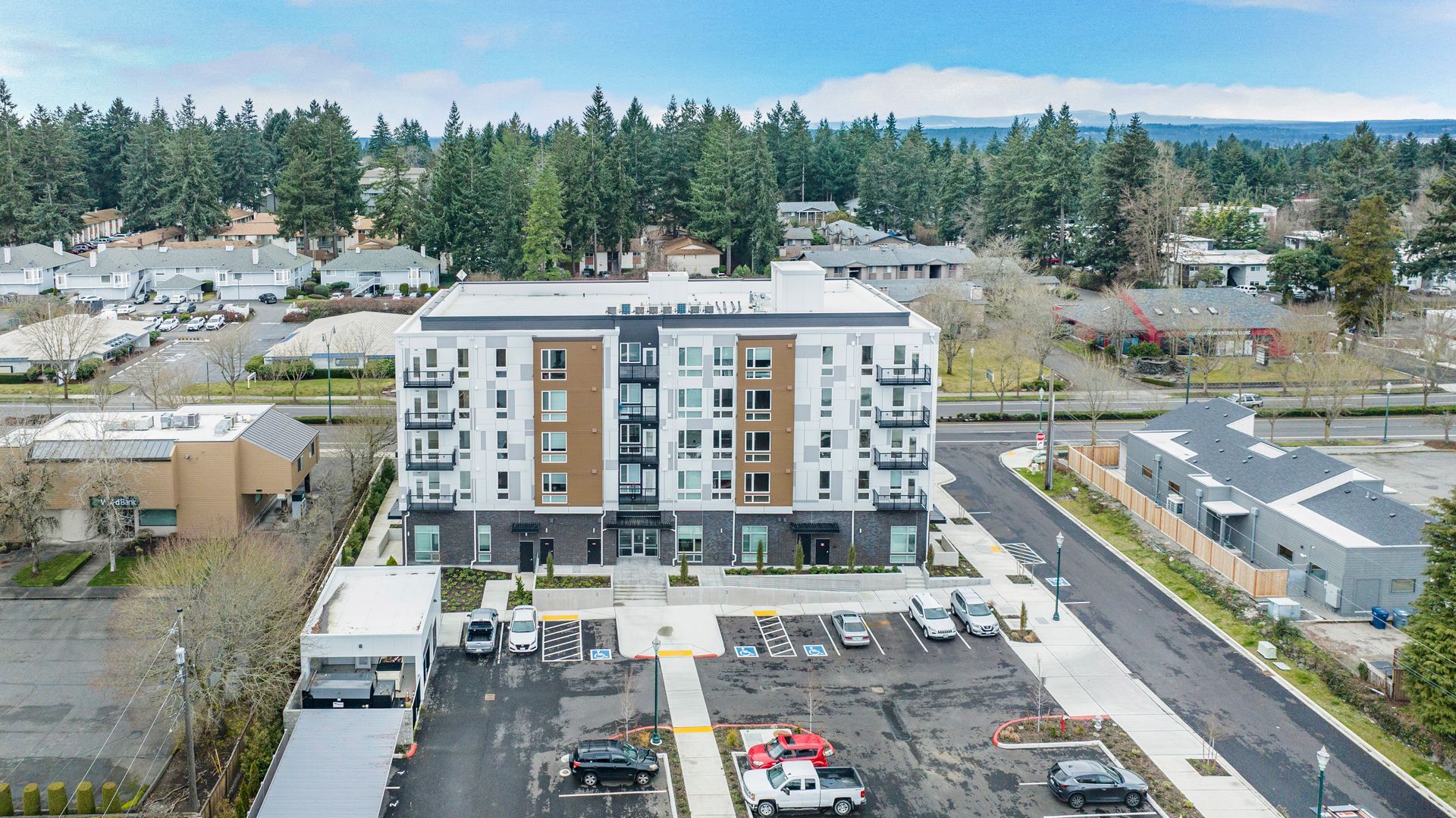 An aerial view of a large apartment building with a parking lot in front of it.