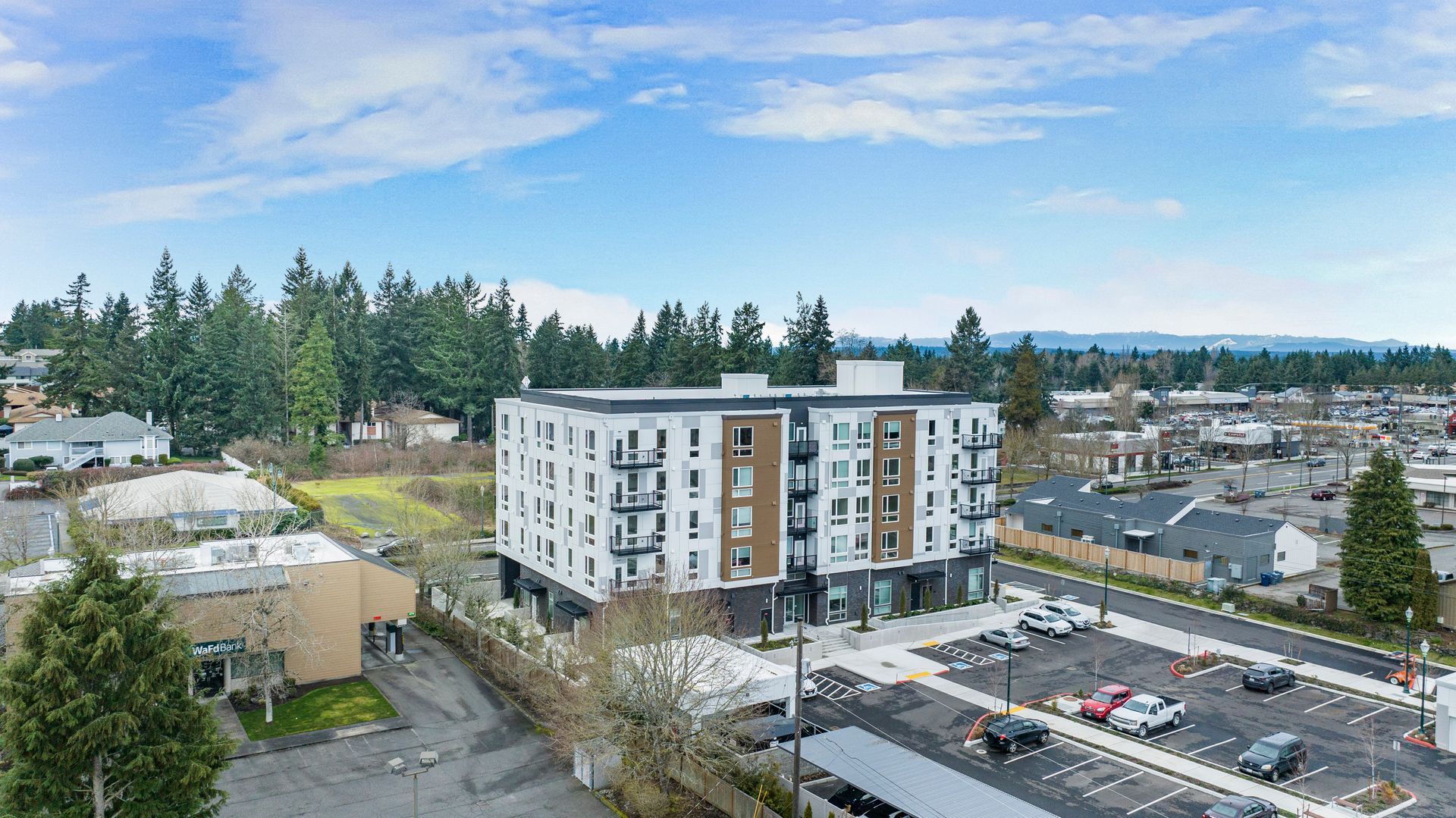 An aerial view of a large apartment building with a parking lot in front of it.