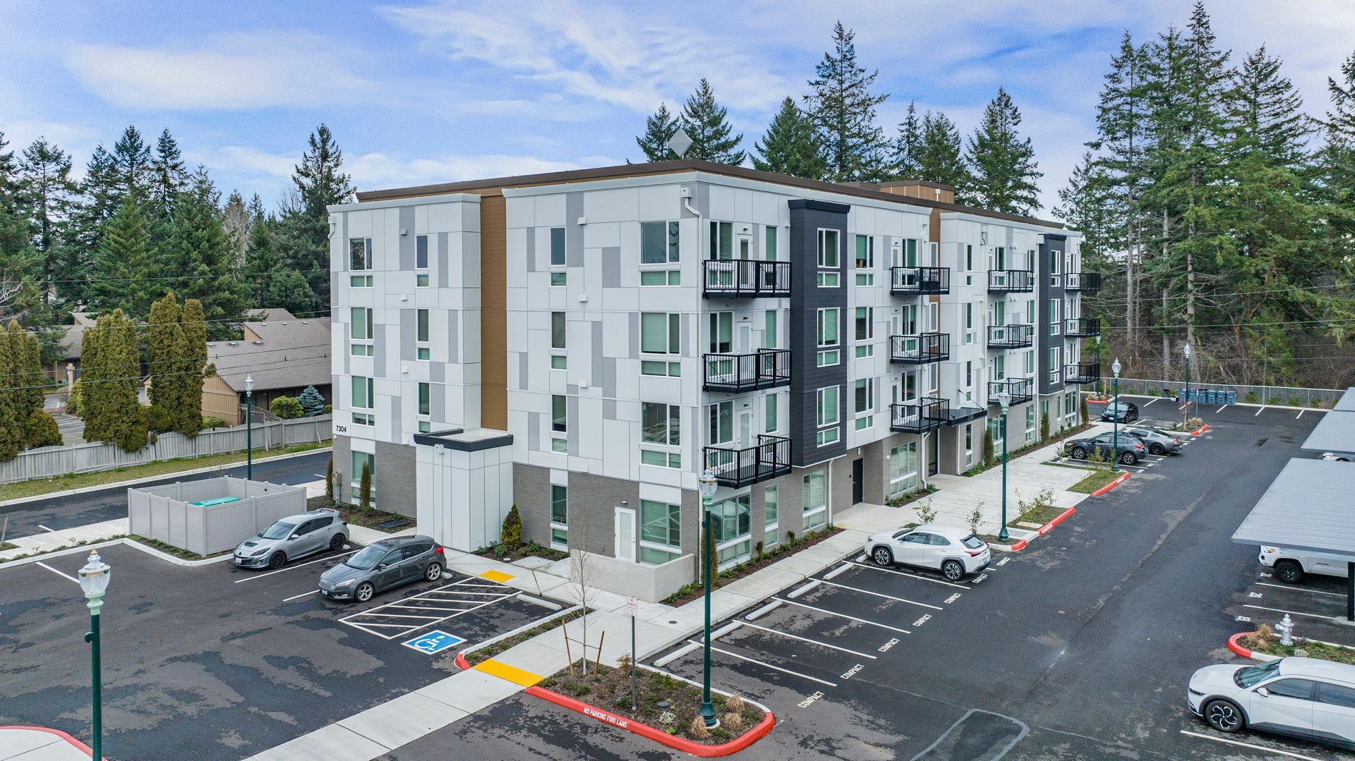 An aerial view of a large apartment building with cars parked in front of it.