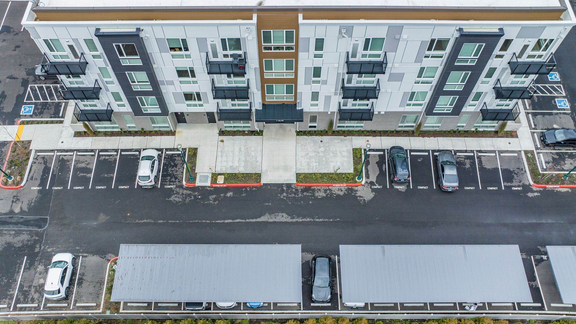 An aerial view of a large apartment building with a parking lot in front of it.