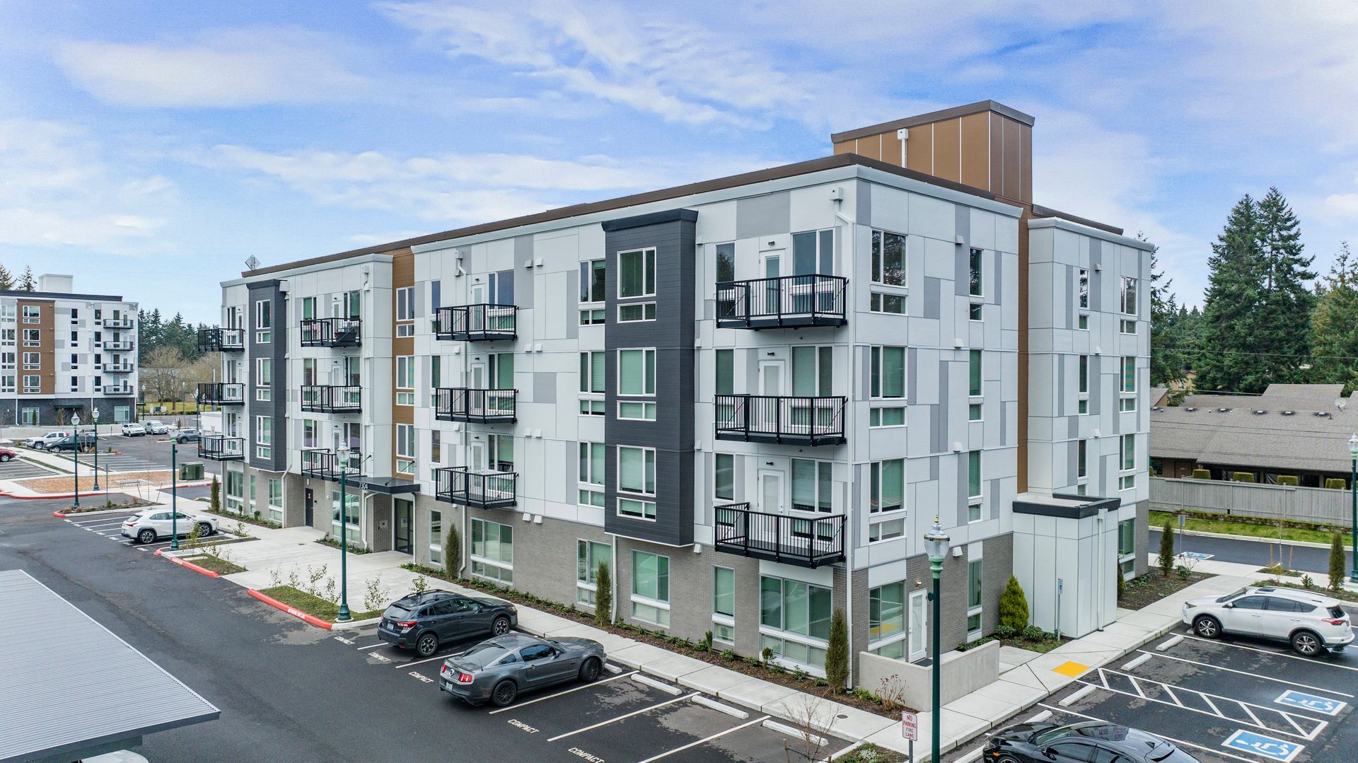 An aerial view of a large apartment building with cars parked in front of it.