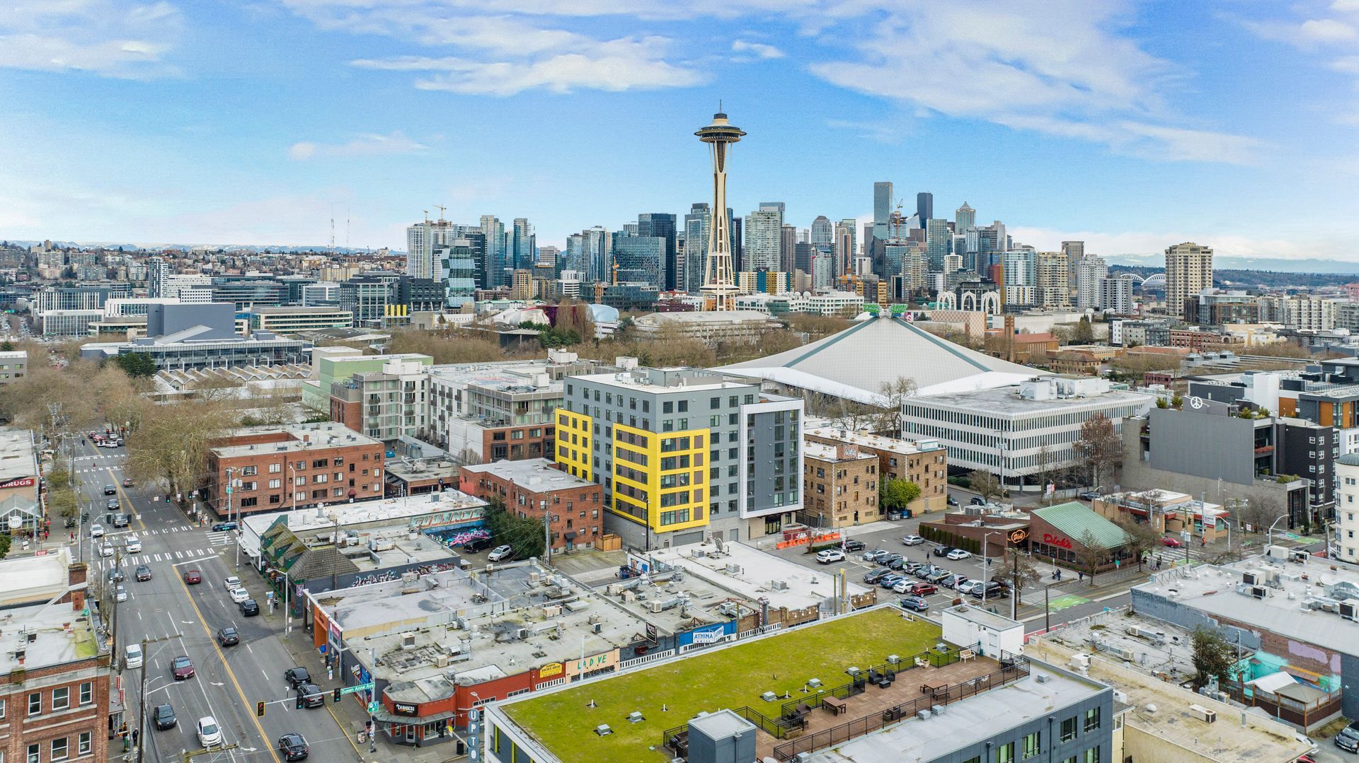 An aerial view of a city with a green roof and a skyline in the background.