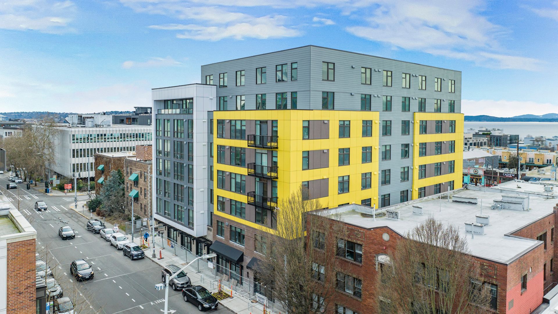 A large building with a yellow facade is sitting on the corner of a city street.