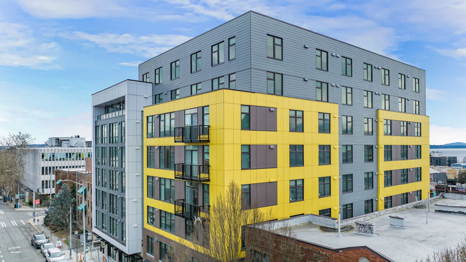 An aerial view of a large yellow and gray building with a lot of windows.