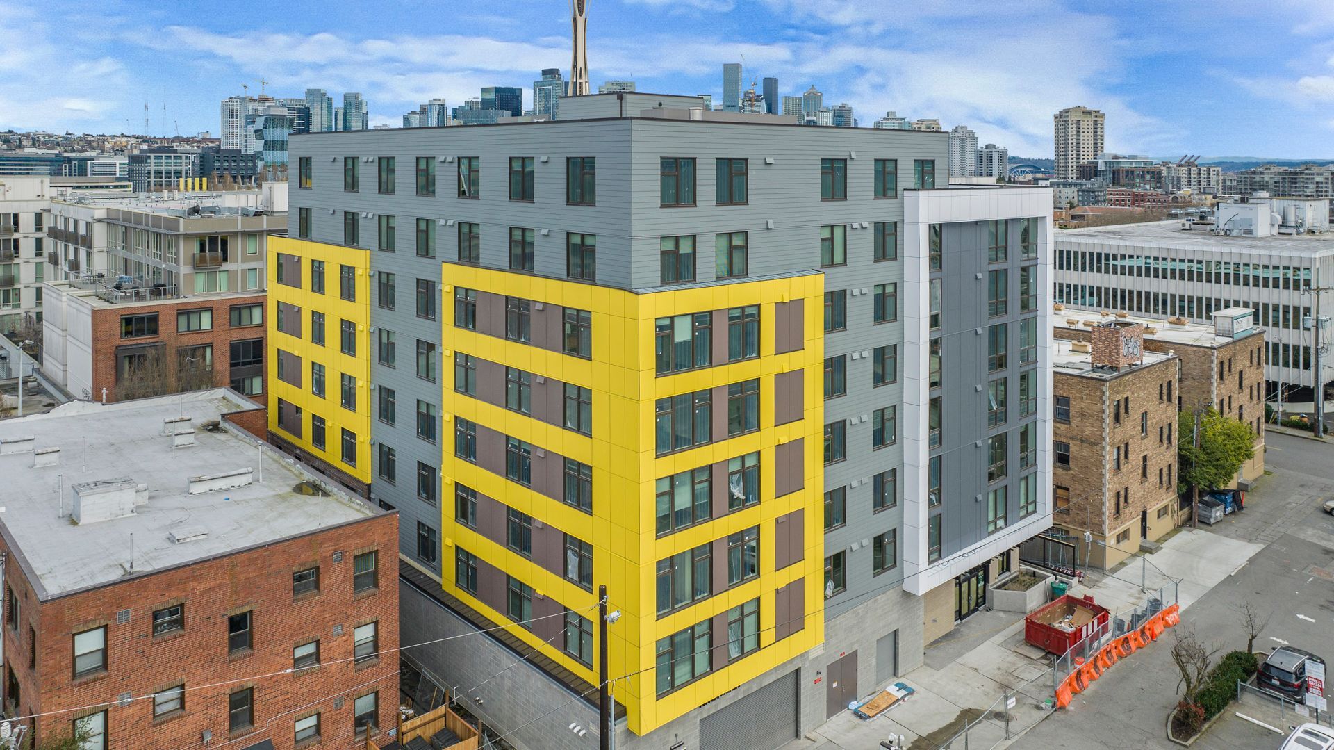 An aerial view of a large building with a yellow corner in the middle of a city.