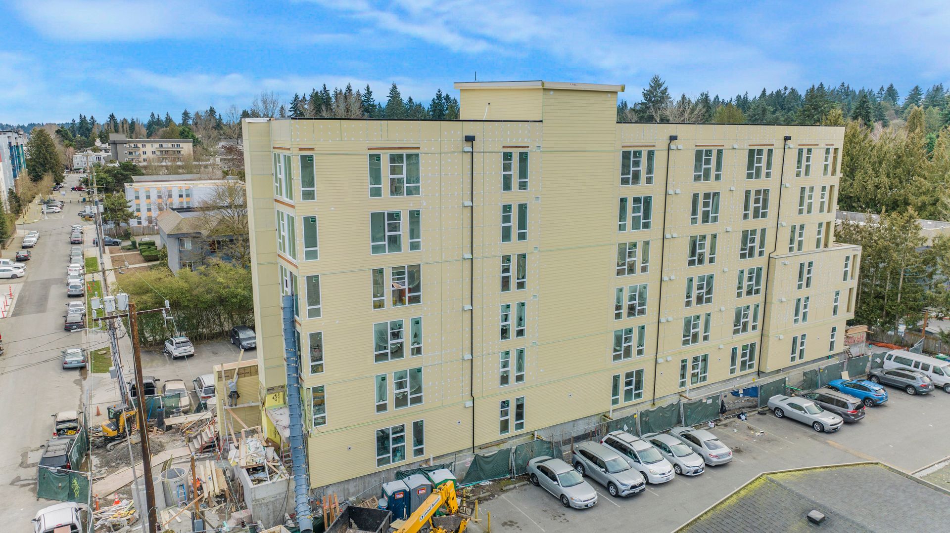 An aerial view of a building under construction with cars parked in front of it.