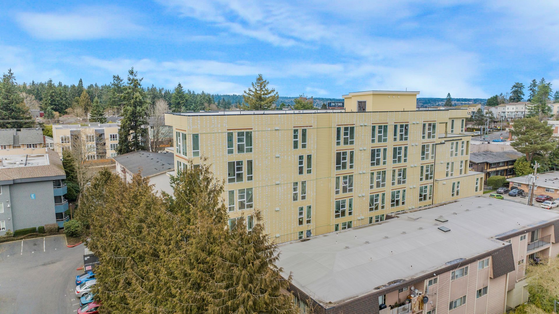 An aerial view of a large building with a lot of windows surrounded by trees.