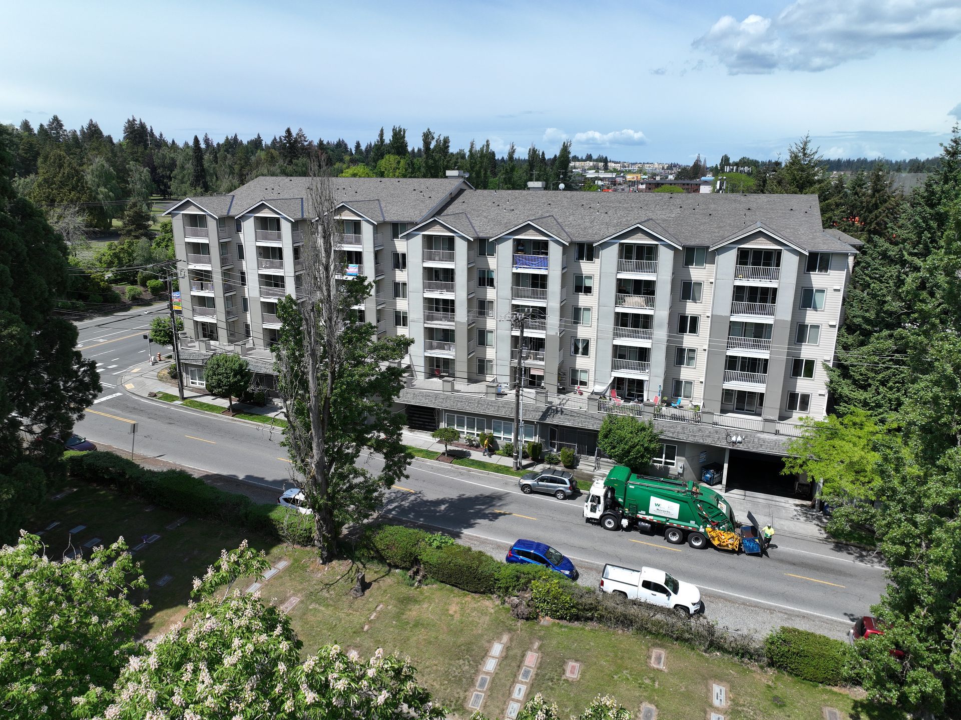 An aerial view of a garbage truck driving down a street in front of a building.