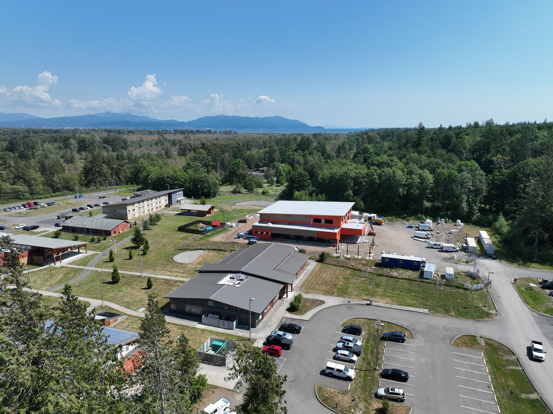 An aerial view of a large building surrounded by trees and a parking lot.