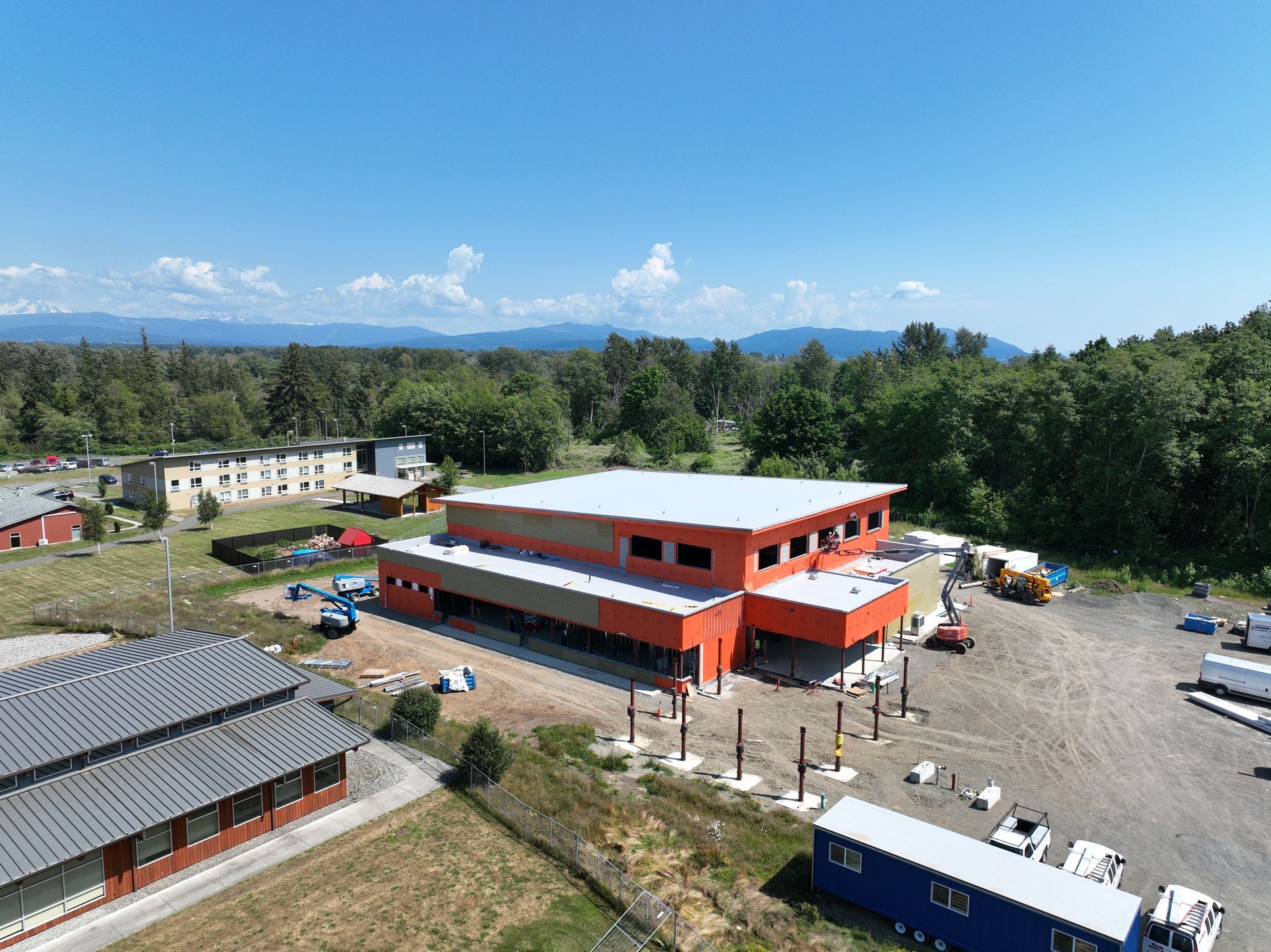 An aerial view of a building under construction with a lot of trucks parked in front of it.