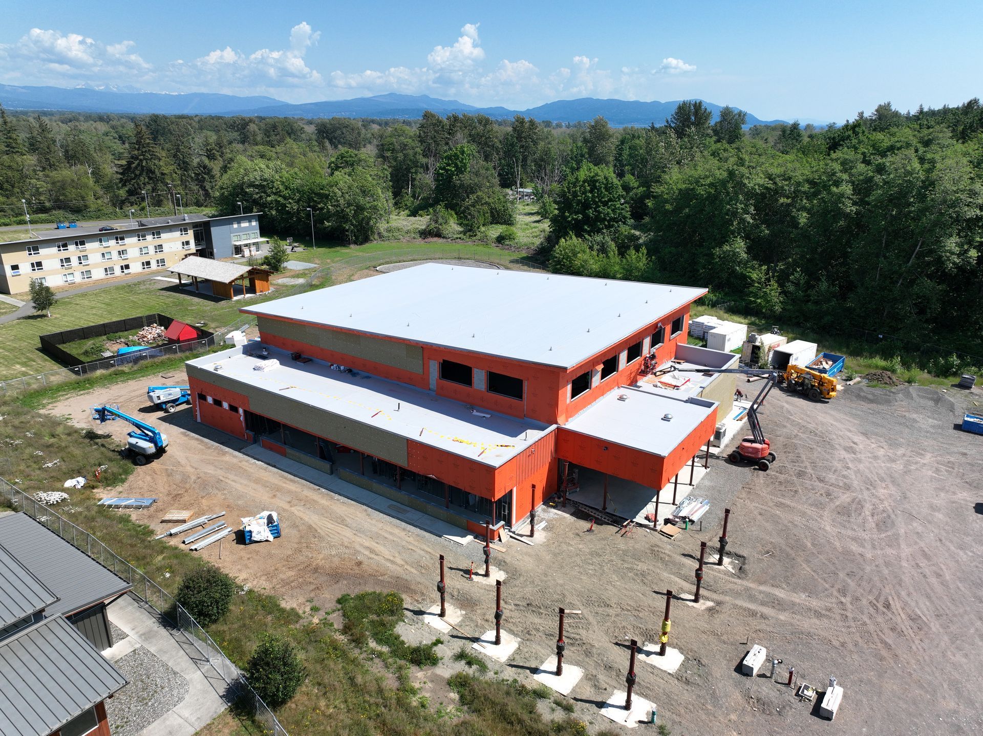 An aerial view of a building under construction with a white roof.
