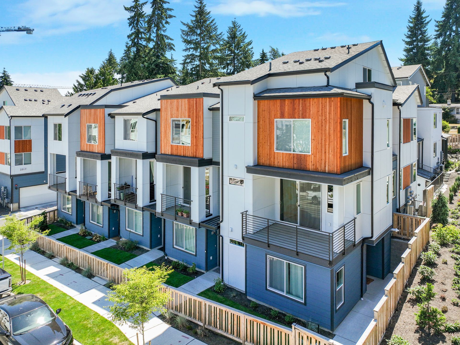 An aerial view of a row of apartment buildings with cars parked in front of them.