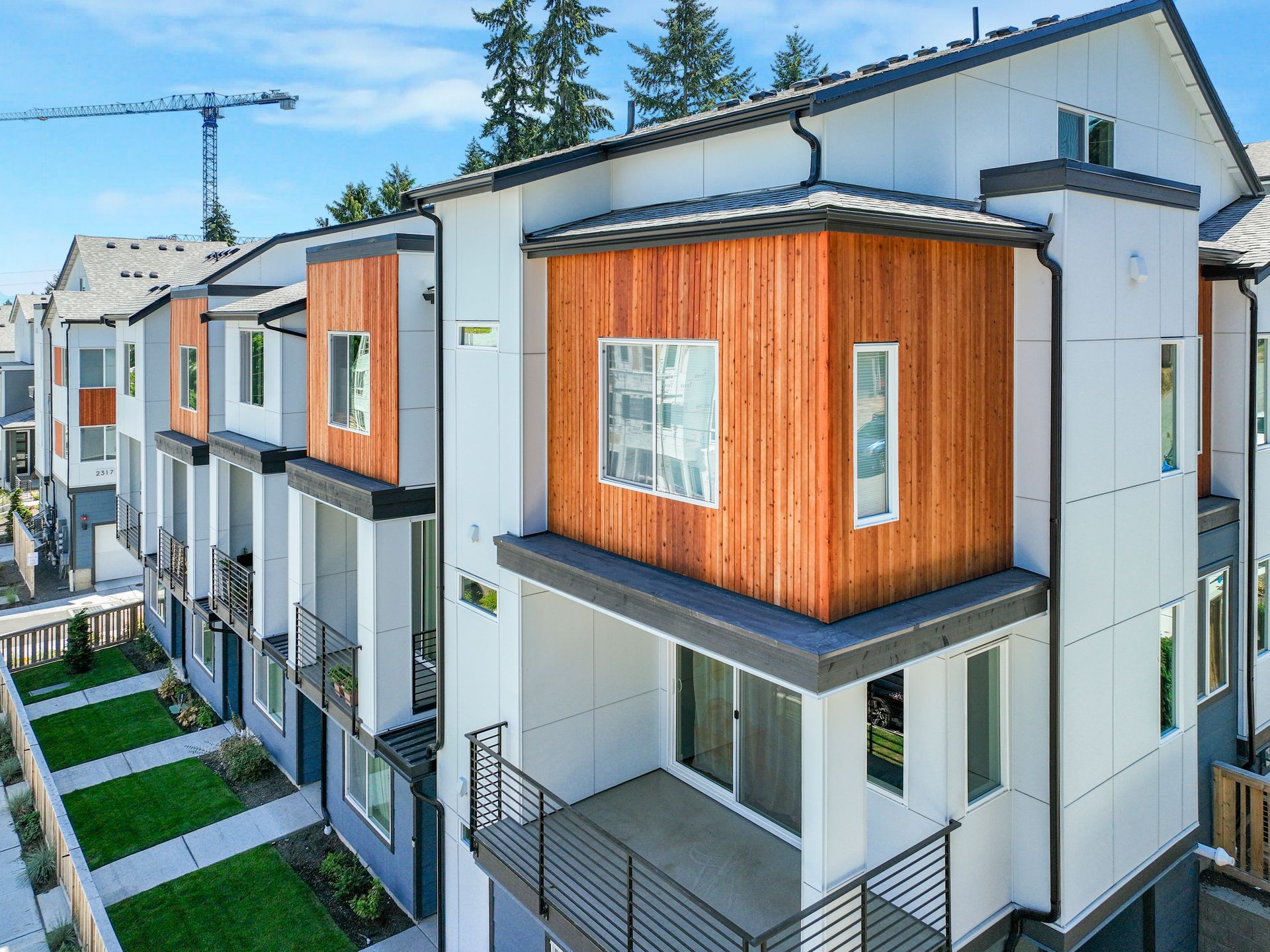 An aerial view of a row of houses with balconies and a crane in the background.