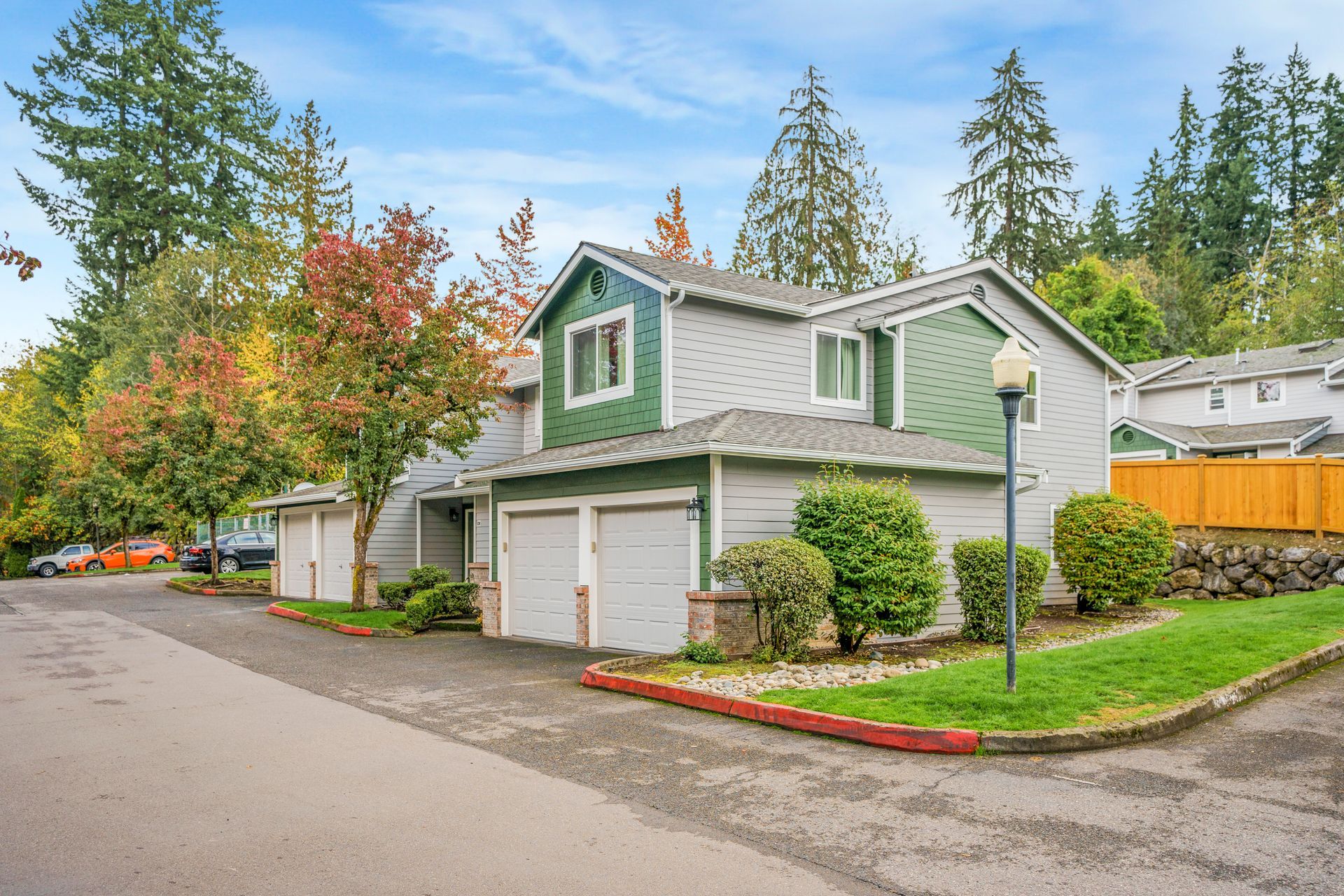 A house with a green siding and two garages