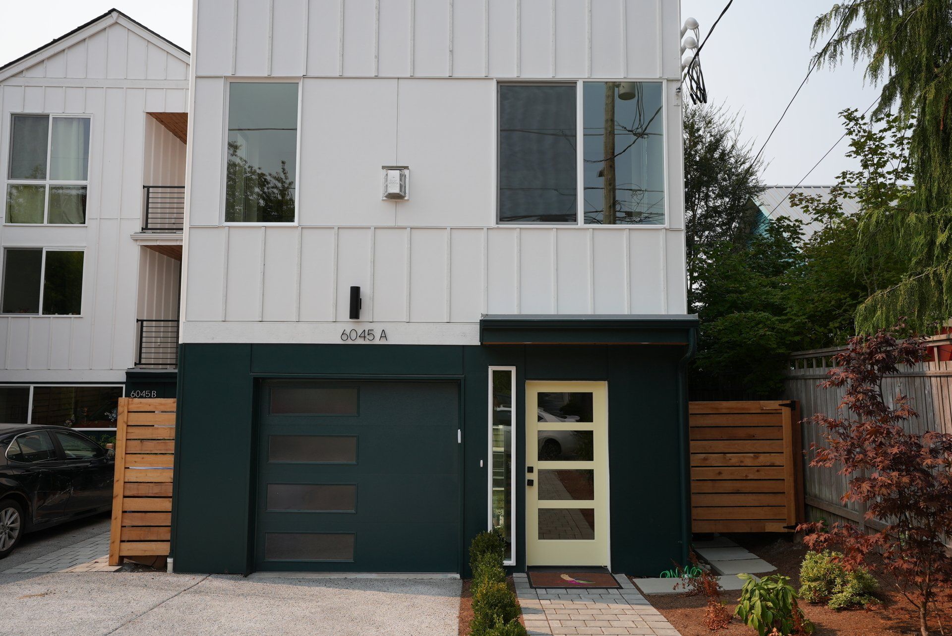 A white house with a green garage door and a white door