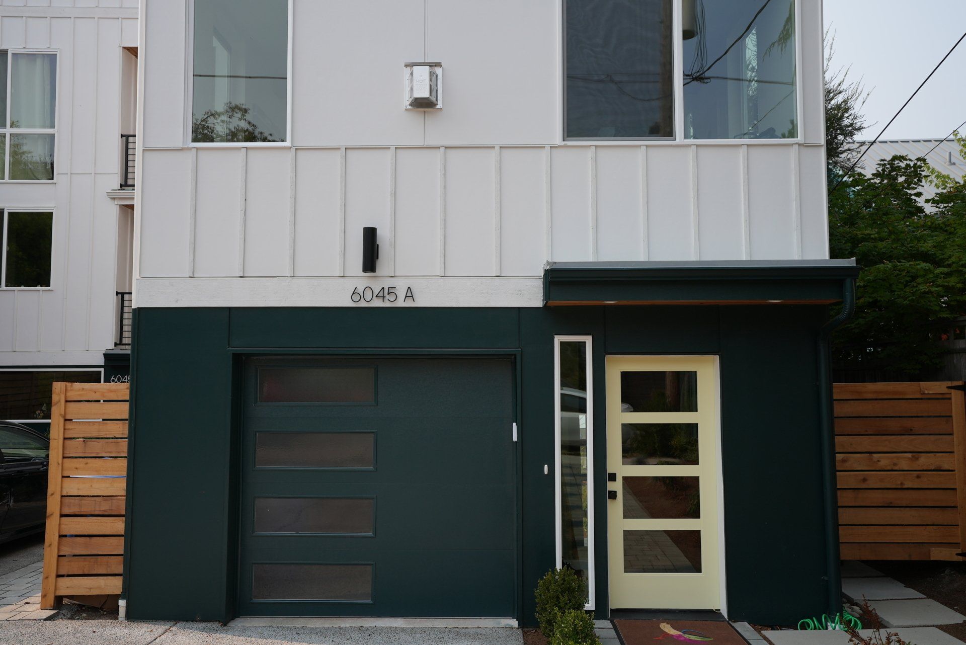 A white house with a green garage door and a yellow door