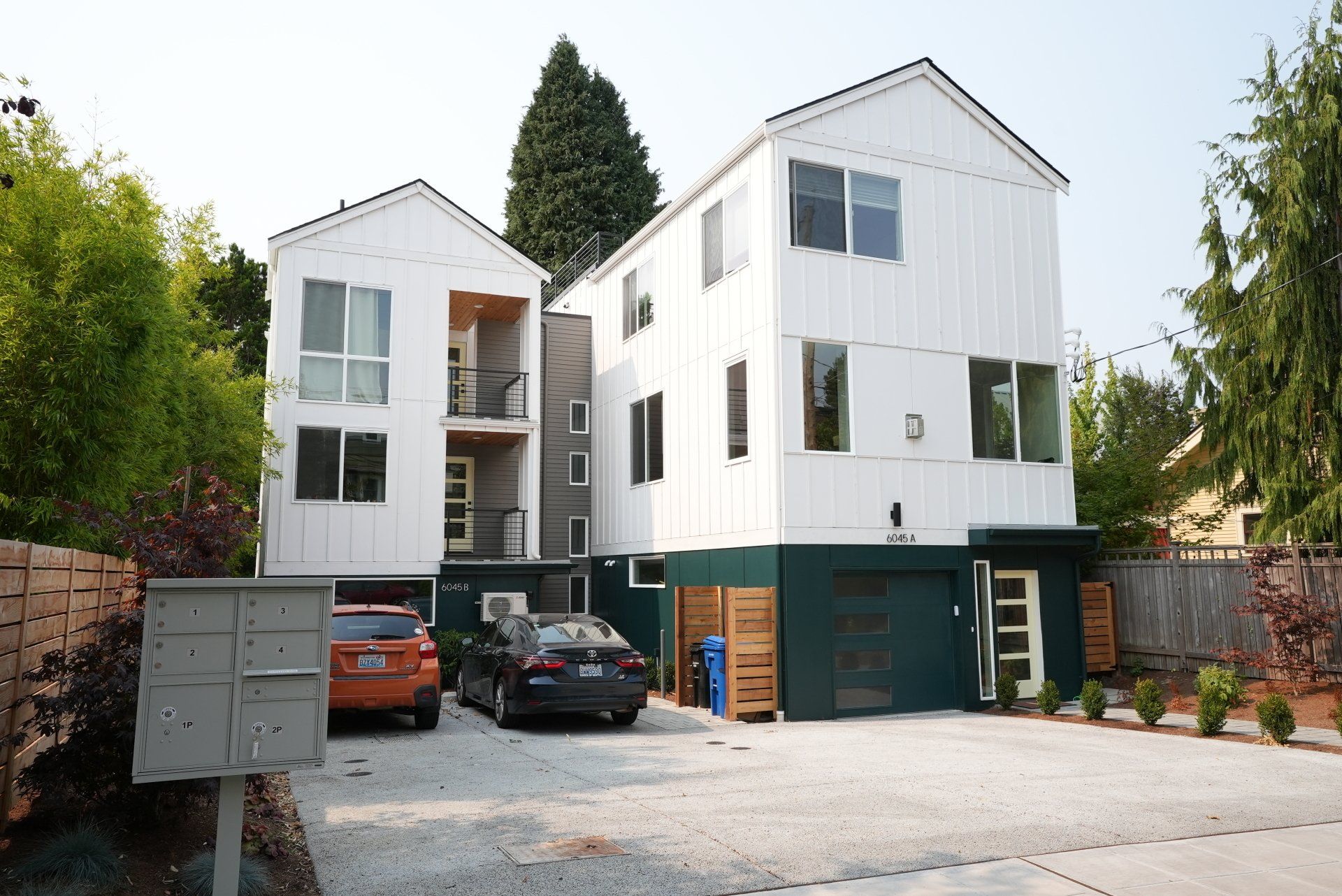 Two cars are parked in front of a white building