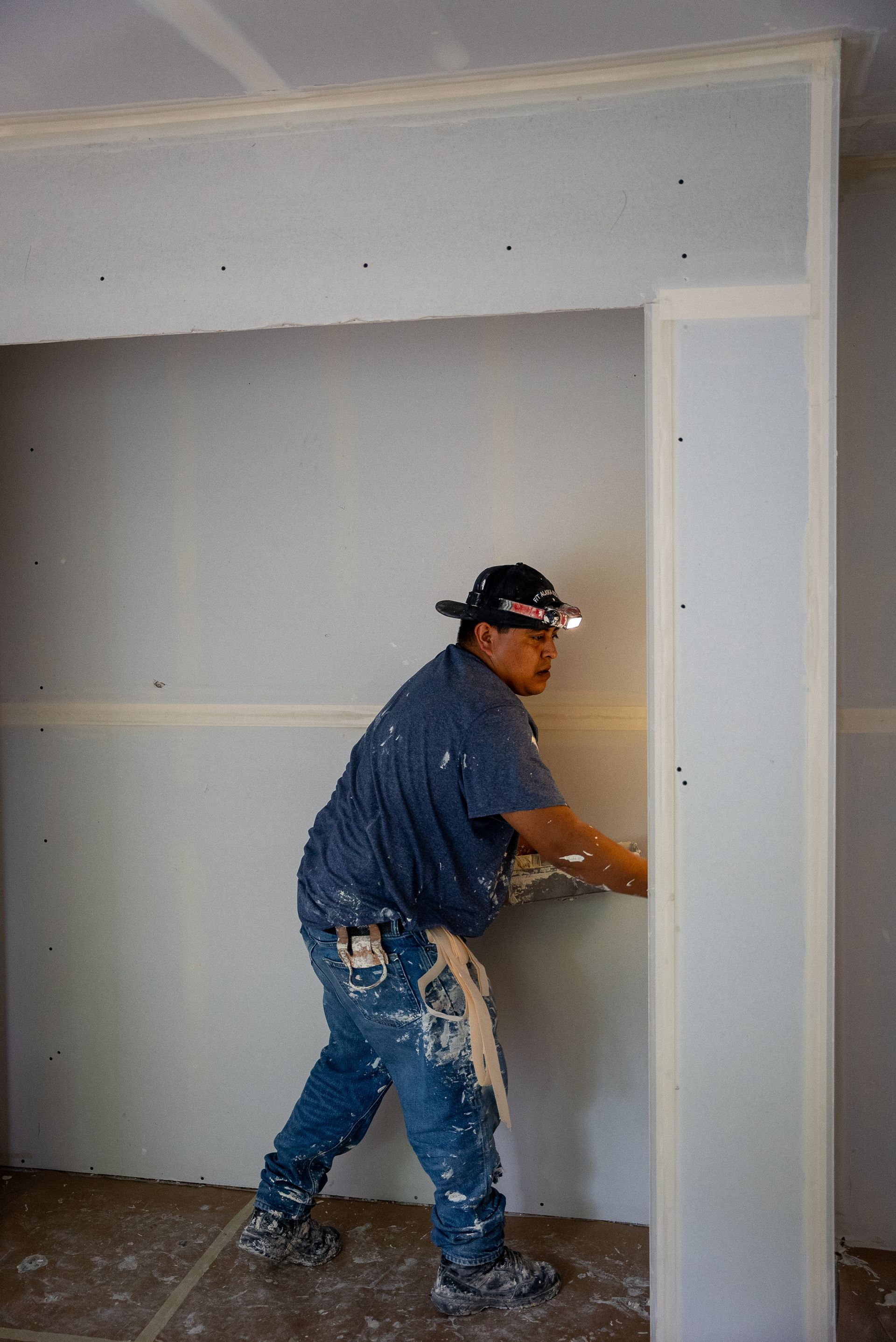 A man is working on a wall in a room.