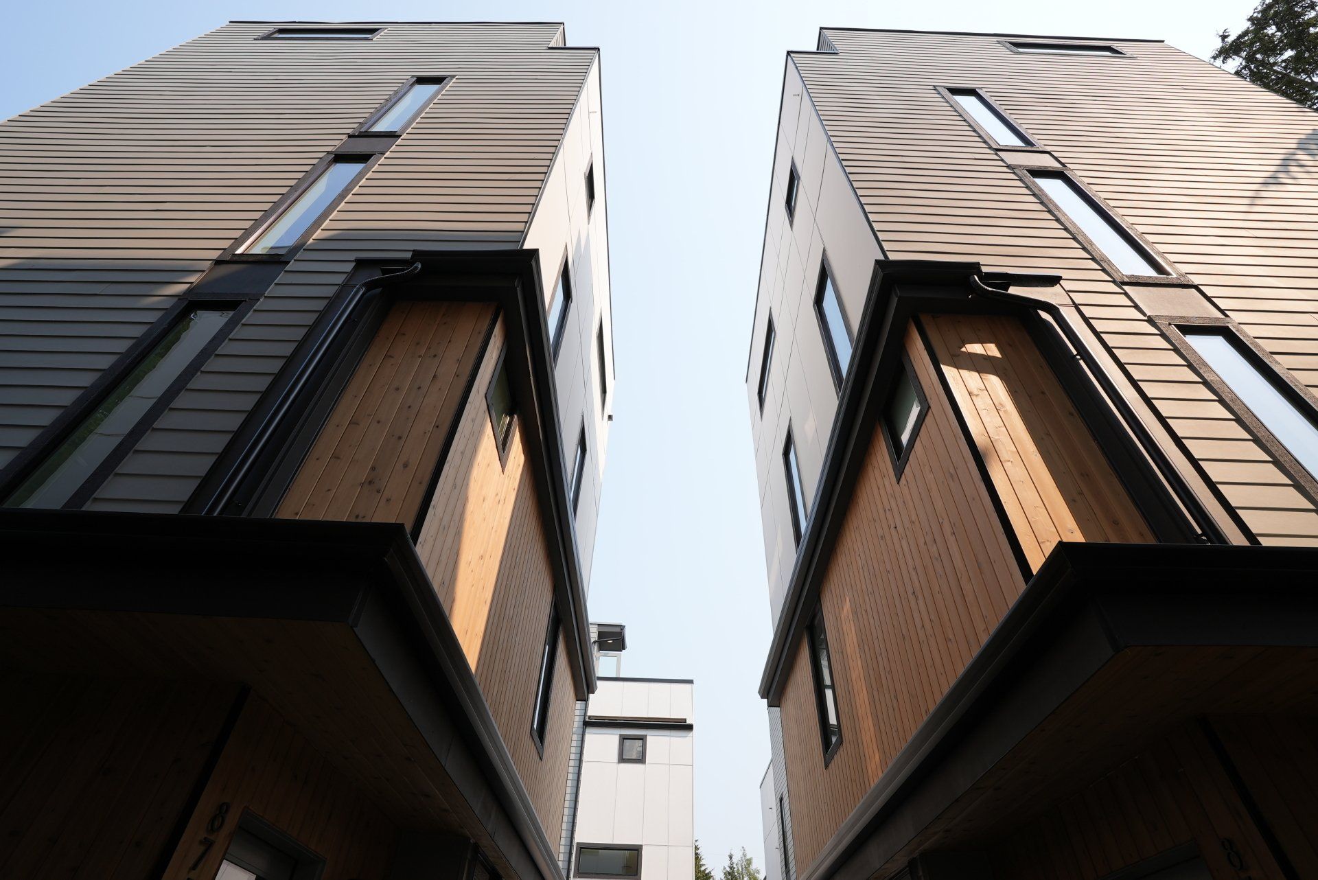 Looking up at two tall buildings with a blue sky in the background